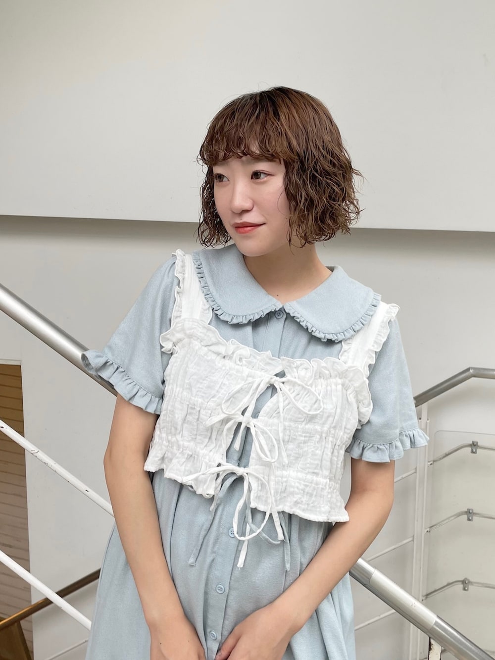 ホワイト系のベスト、ブルー系のワンピース、ホワイト系のサンダルを着用したレディースの夏コーディネートの3枚目の写真