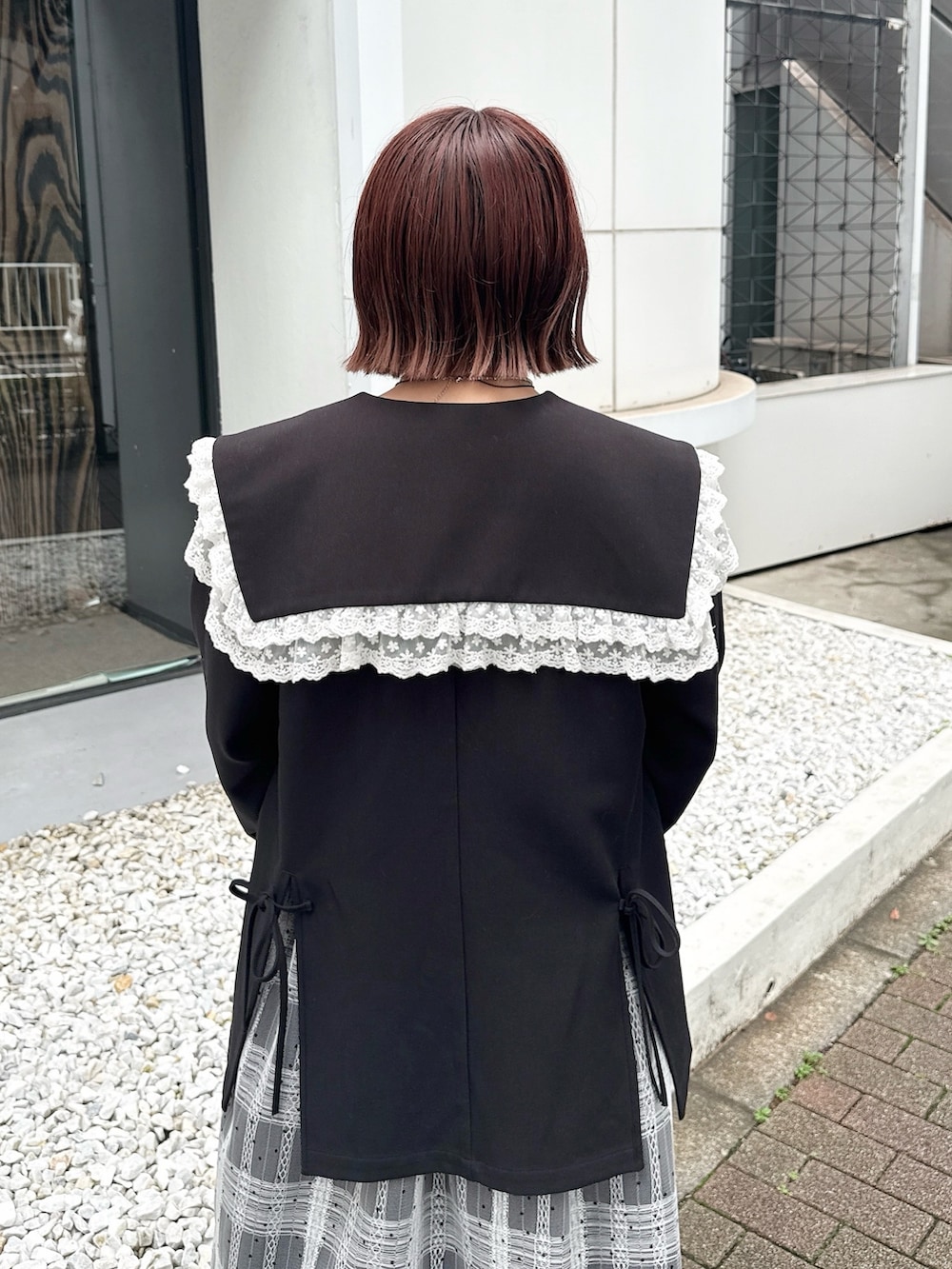 レッド系のハンドバッグ、ブラック系のテーラードジャケット、ブラック系のワンピースを着用したレディースの夏コーディネートの6枚目の写真