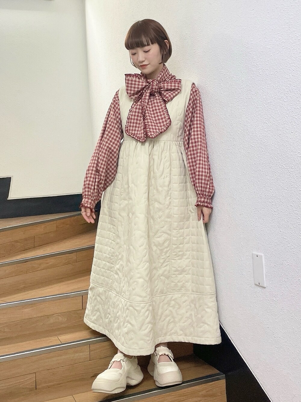 ホワイト系のダウンジャケット/コート、レッド系のシャツ/ブラウス、ホワイト系のワンピースを着用したレディースの冬コーディネートの7枚目の写真