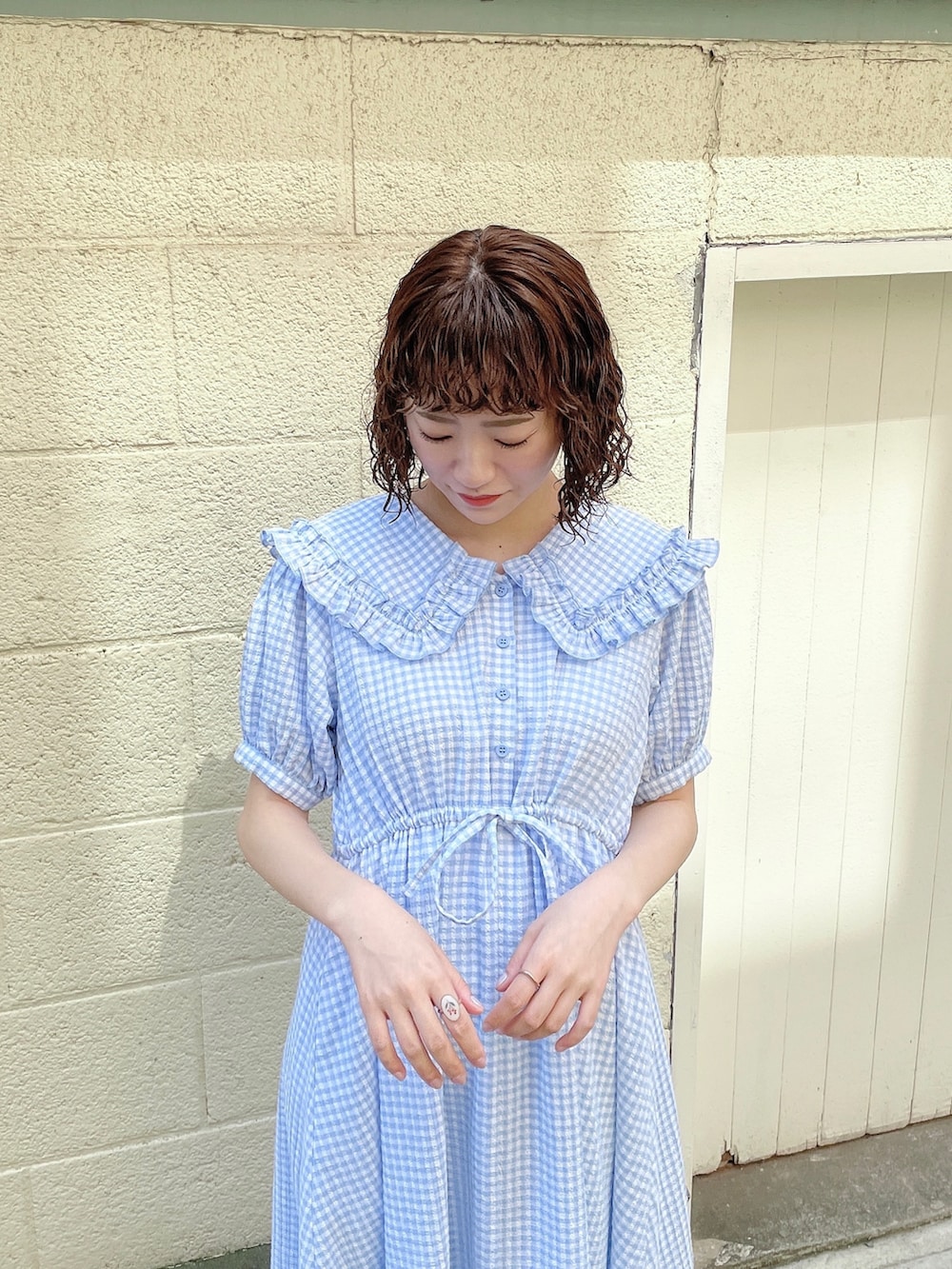 ホワイト系のカーディガン/ボレロ、ブルー系のワンピース、ゴールド系のパンプスを着用したレディースの春コーディネートの6枚目の写真