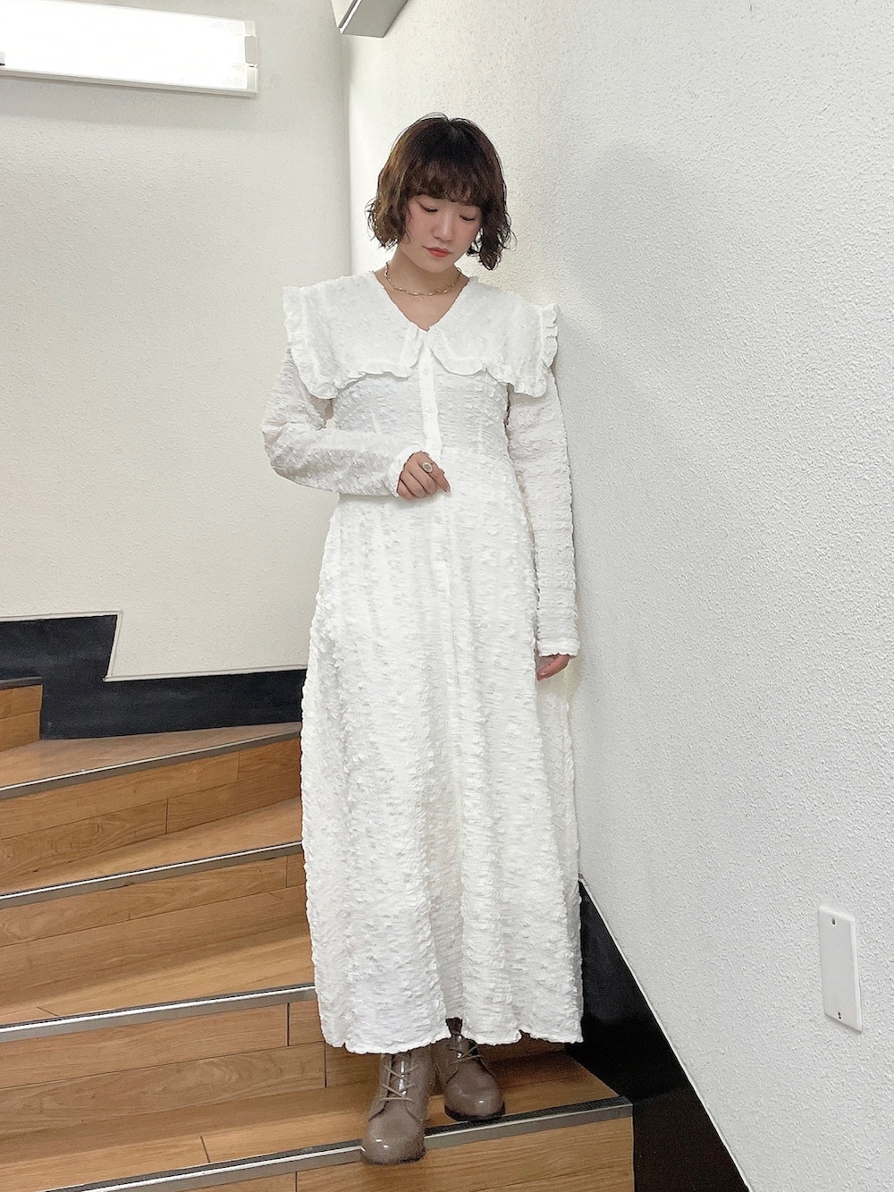 ホワイト系のワンピース、ベージュ系のブーツを着用したレディースの秋コーディネートの2枚目の写真