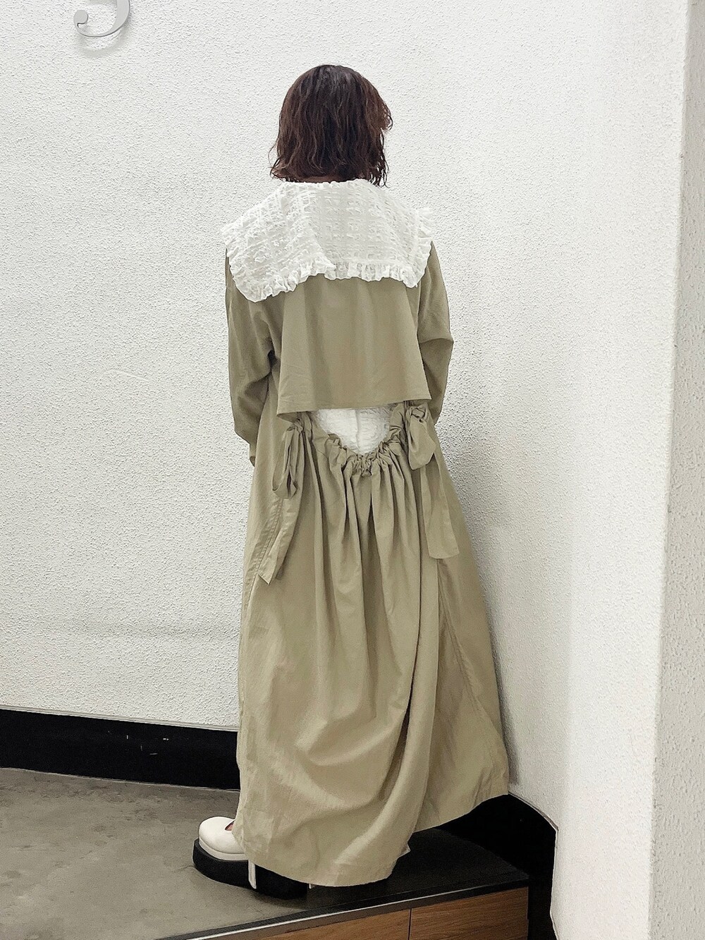 ホワイト系のワンピース、ベージュ系のトレンチコート、ホワイト系のパンプスを着用したレディースの冬コーディネートの3枚目の写真