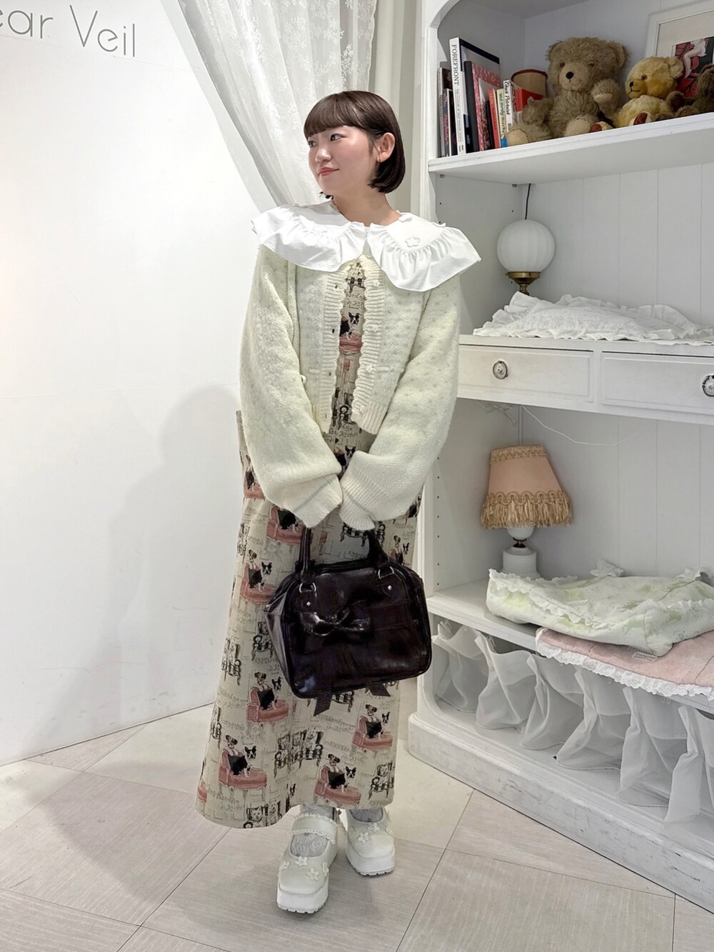 ベージュ系のジャンパースカート、ホワイト系のシャツ/ブラウス、ホワイト系のカーディガン/ボレロを着用したレディースの夏コーディネートの2枚目の写真