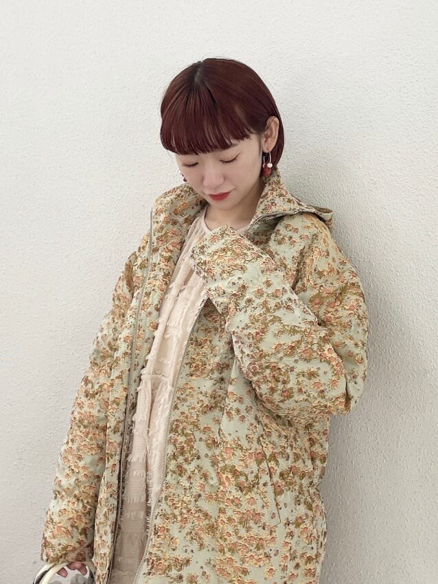 イエロー系のマウンテンパーカー、グリーン系のハンドバッグ、ベージュ系のドレスを着用したレディースの夏コーディネートの4枚目の写真