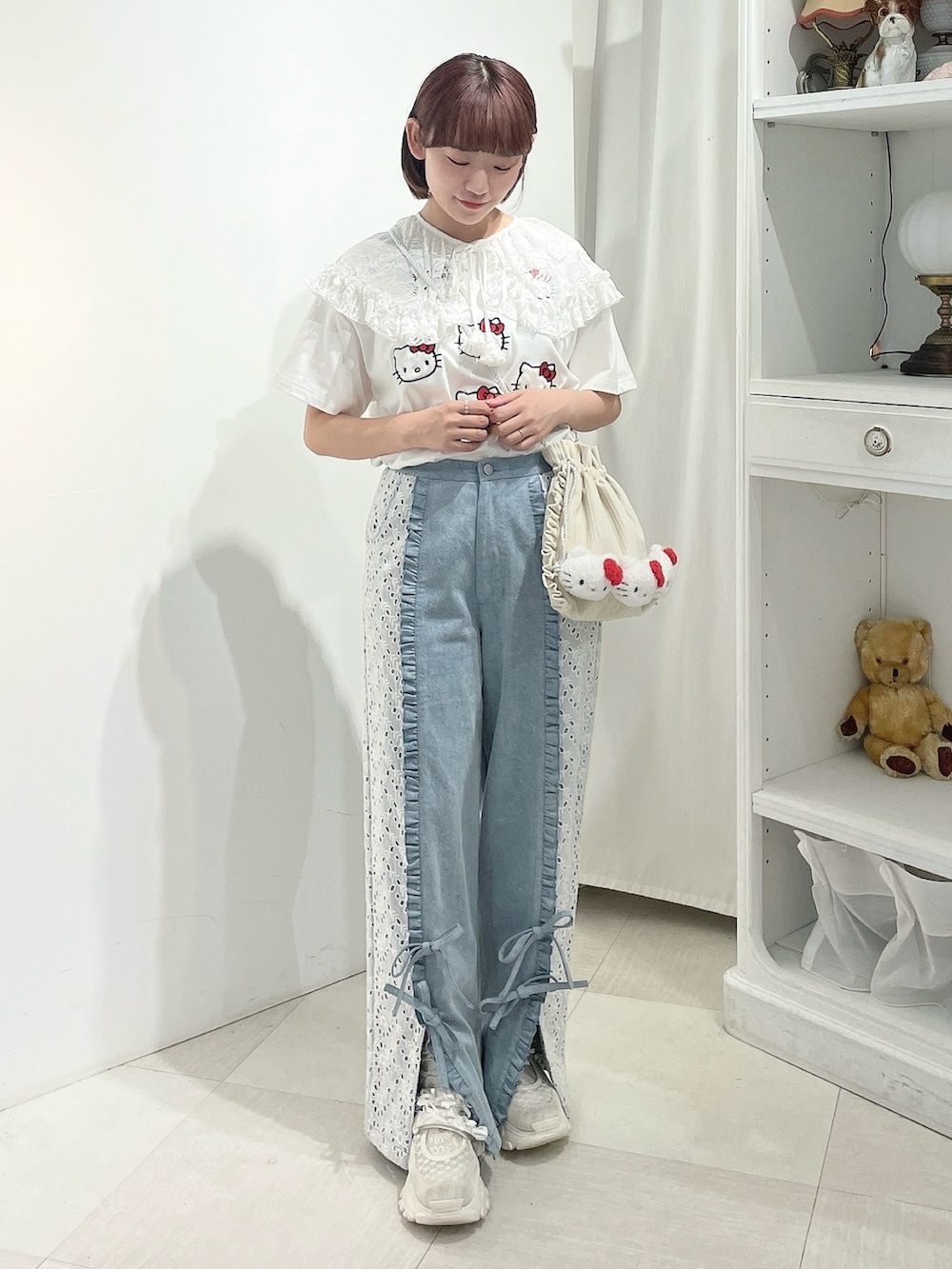 ブルー系のデニムパンツ、ホワイト系のスニーカー、ホワイト系のショルダーバッグを着用したレディースの春コーディネートの2枚目の写真