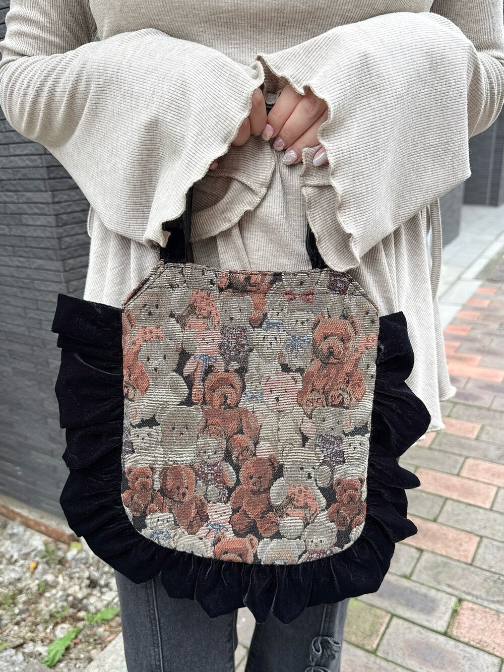 ブラウン系のニット/セーター、ブラック系のハンドバッグ、ブラック系のデニムパンツを着用したレディースの夏コーディネートの4枚目の写真