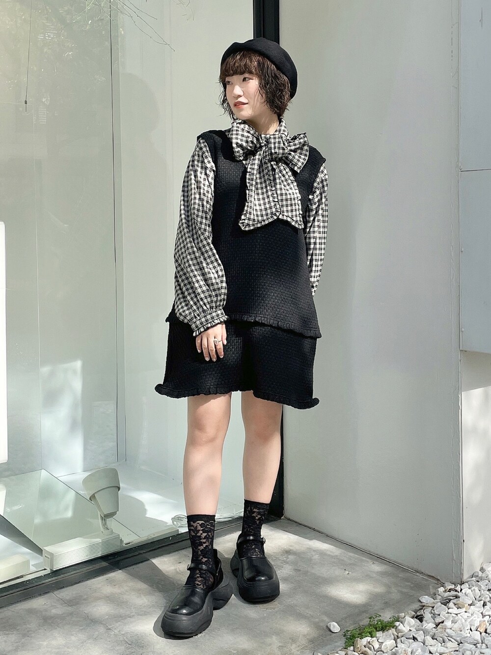 ブラック系のスニーカー、レッド系のチェスターコート、ブラック系のジャンパースカートを着用したレディースの秋コーディネートの5枚目の写真