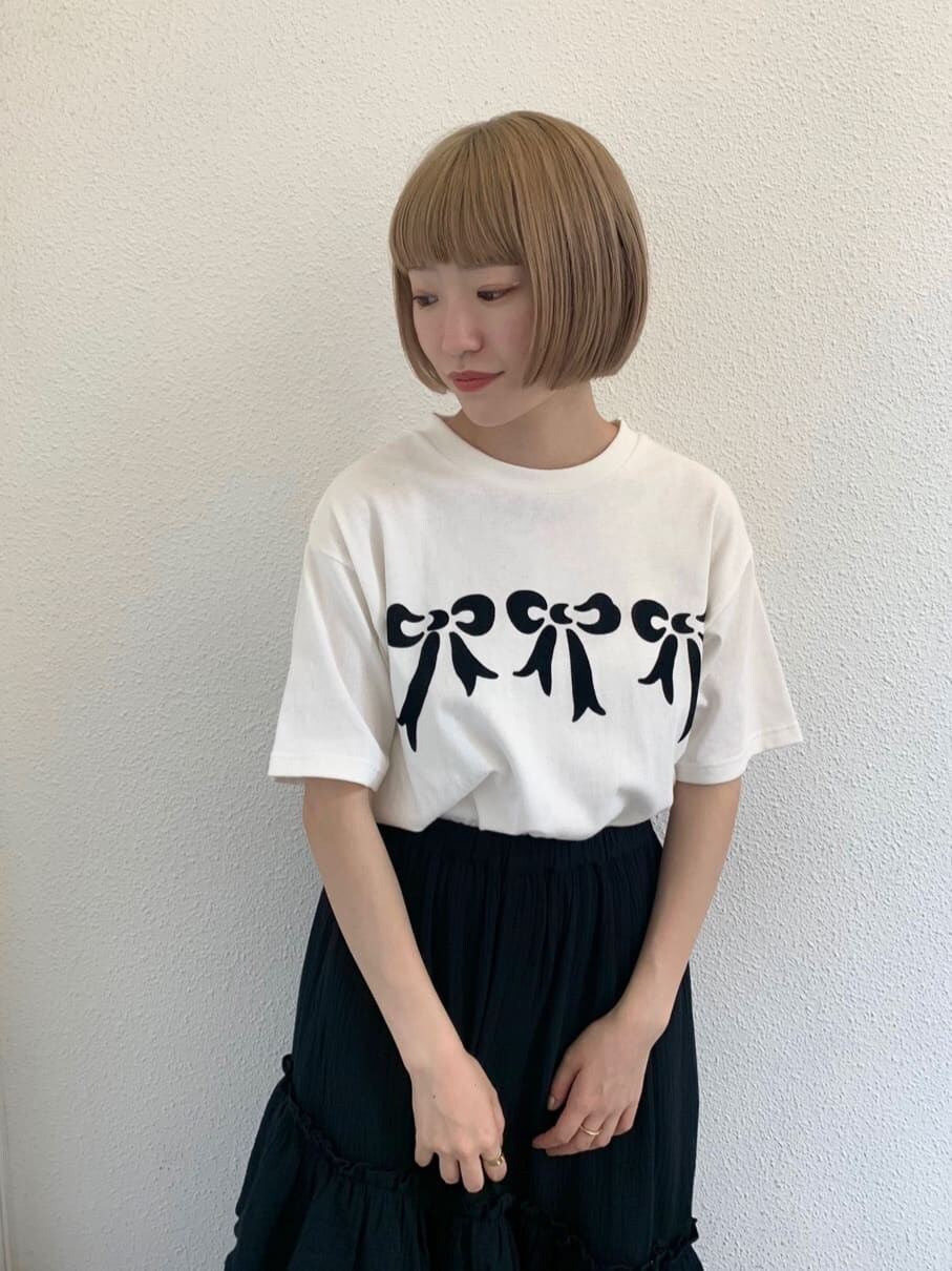 ブラック系のスカート、ブラック系のスニーカー、ホワイト系のTシャツ/カットソーを着用したレディースの夏コーディネートの2枚目の写真