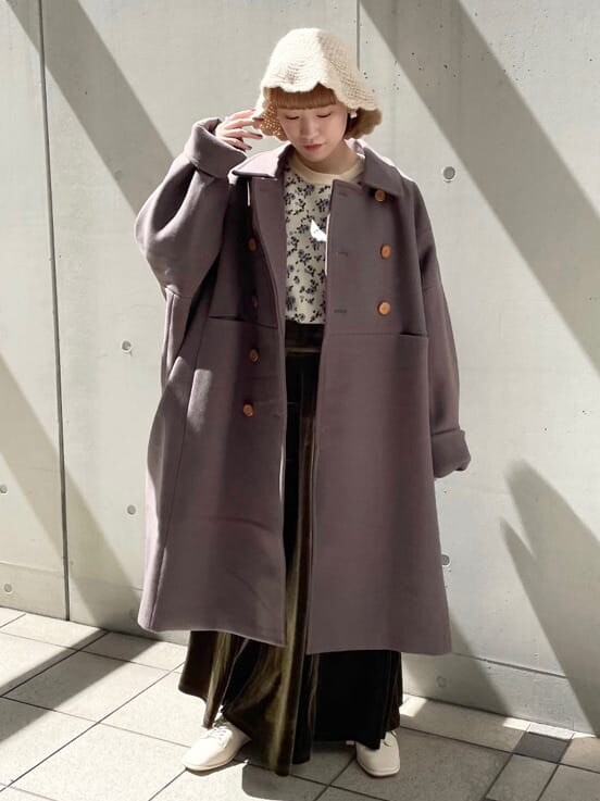 グリーン系のチェスターコート、ホワイト系のその他シューズ、ベージュ系のスカートを着用したレディースの秋コーディネートの2枚目の写真