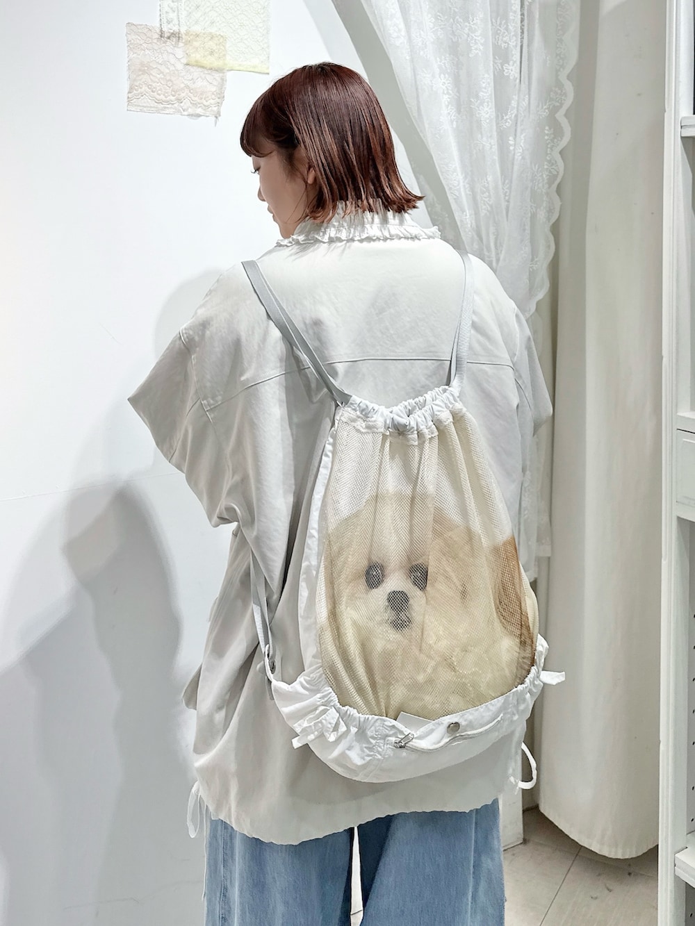 ホワイト系のブルゾン、ホワイト系のバックパック/リュック、ブルー系のデニムパンツを着用したレディースの冬コーディネートの6枚目の写真