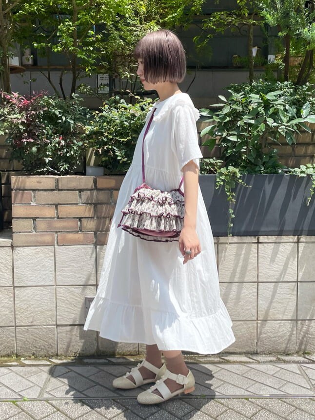 ホワイト系のワンピース、ホワイト系のパンプス、パープル系のハンドバッグを着用したレディースの夏コーディネートの2枚目の写真