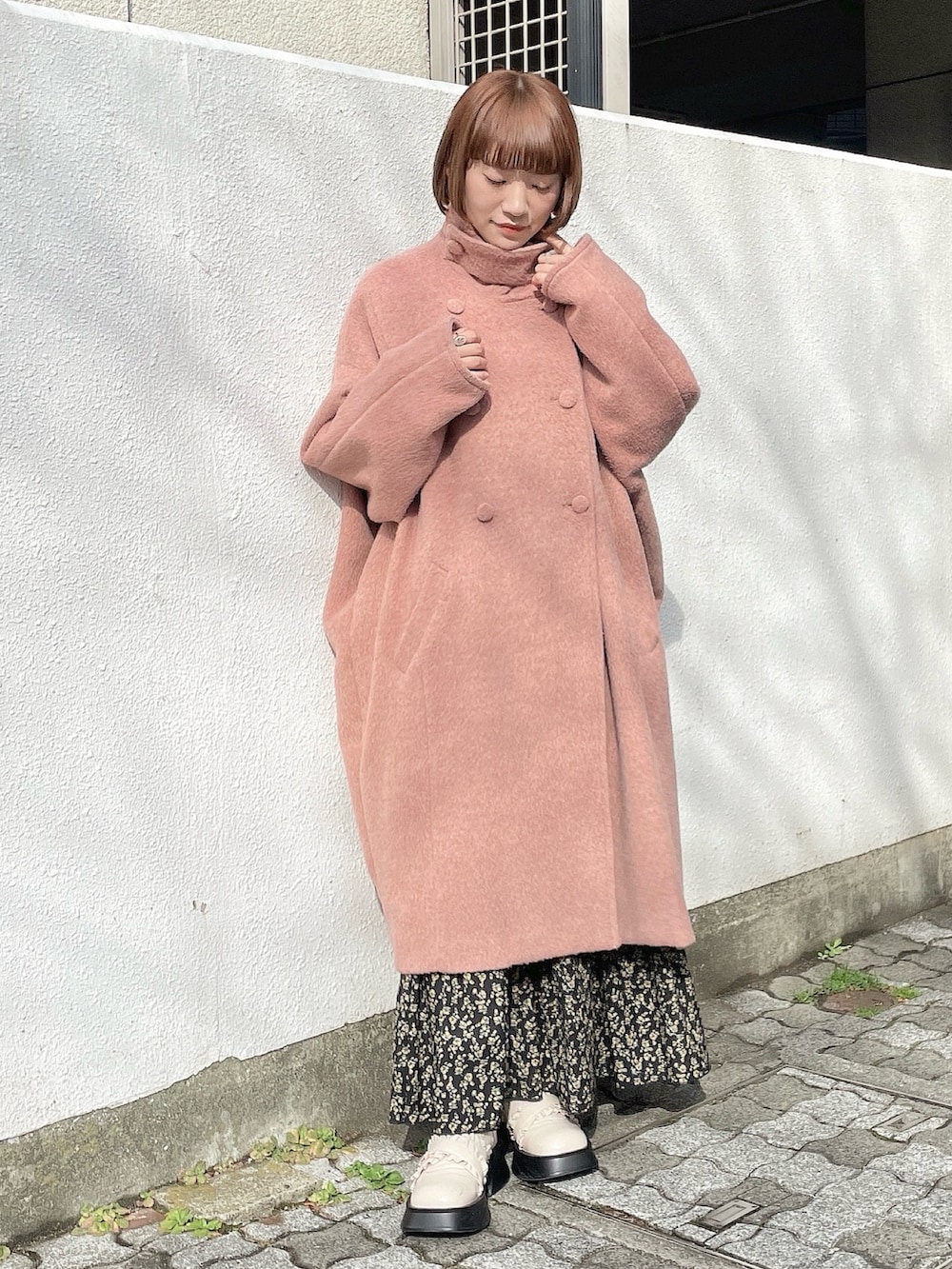 ピンク系のチェスターコート、ブラック系のスカート、グレー系のシャツ/ブラウスを着用したレディースの冬コーディネートの2枚目の写真