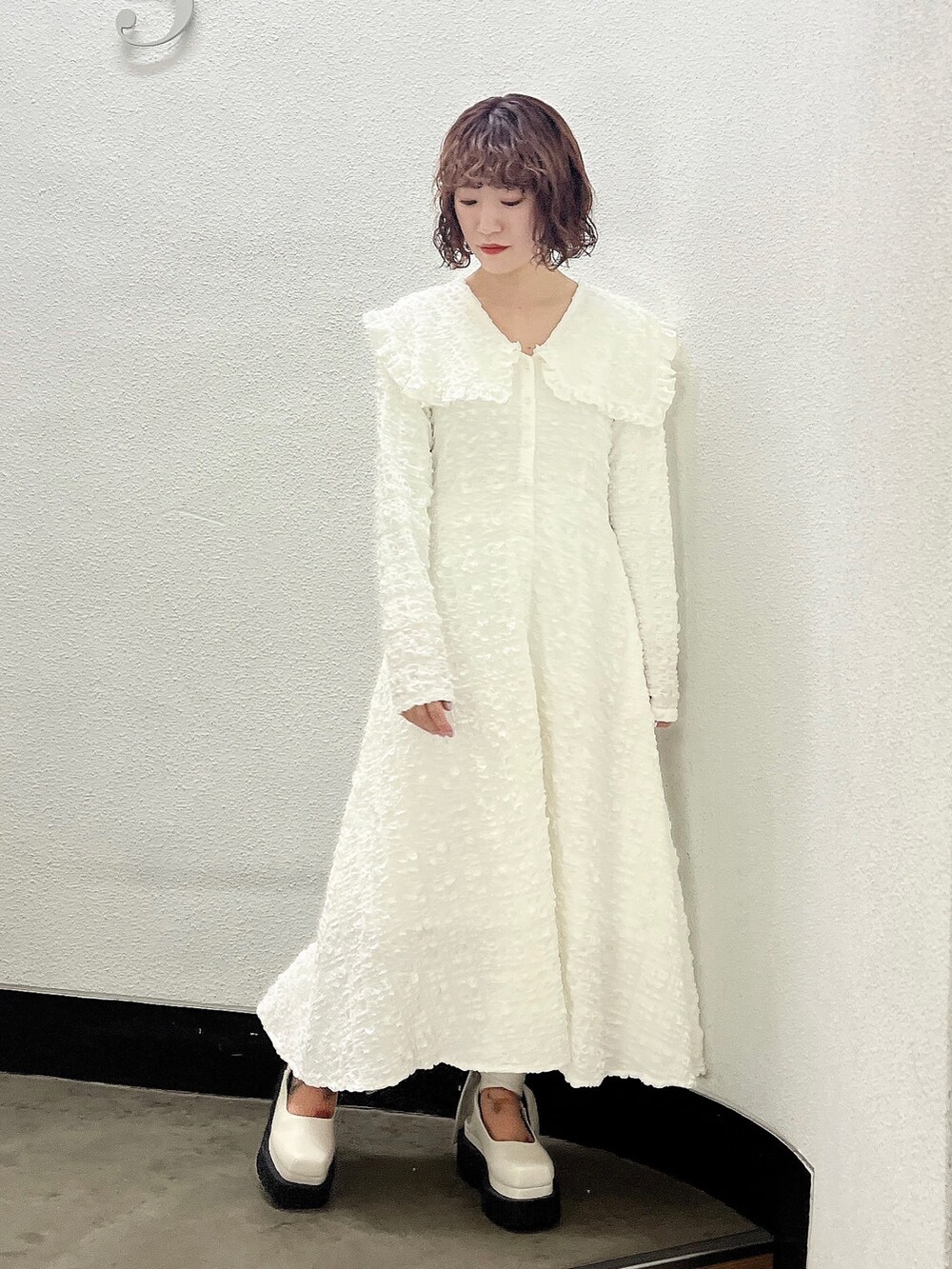 ホワイト系のワンピース、ベージュ系のトレンチコート、ホワイト系のパンプスを着用したレディースの冬コーディネートの6枚目の写真