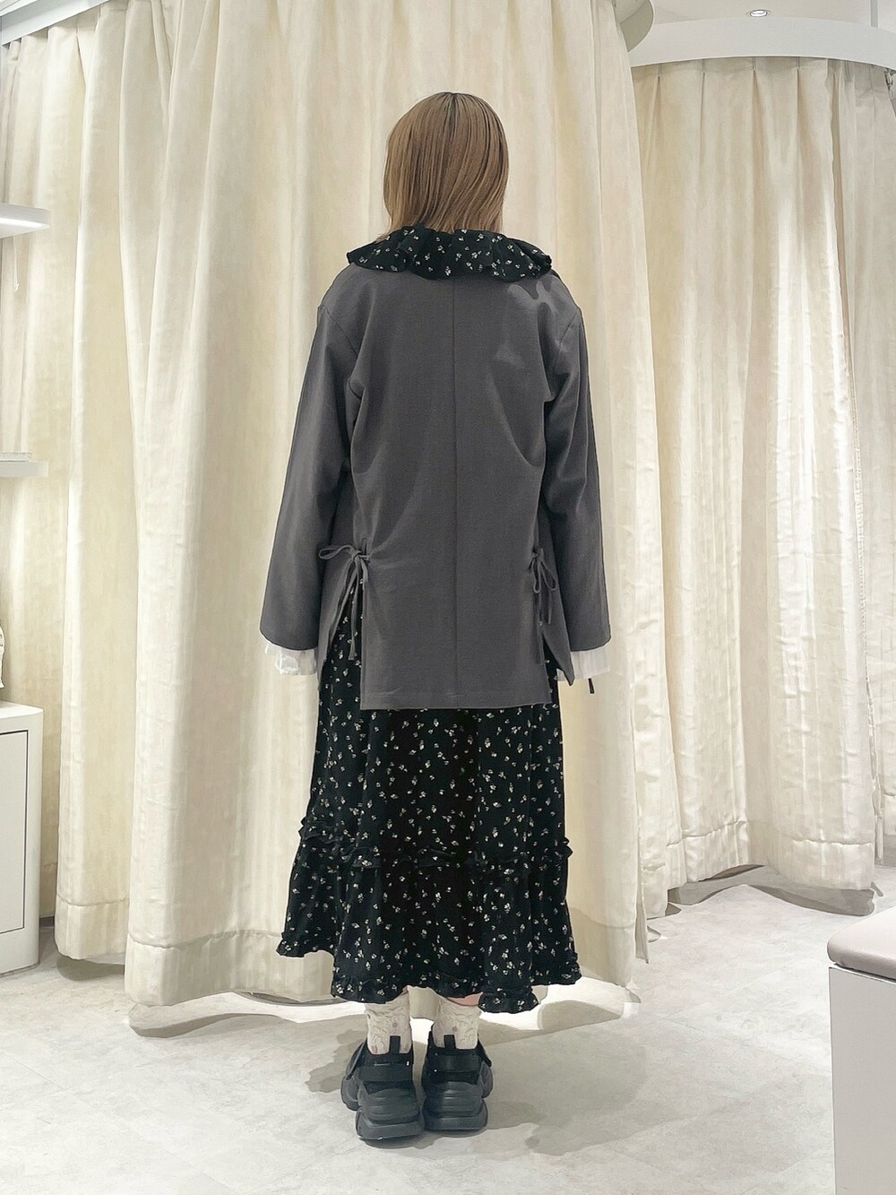 ブラック系のワンピース、グレー系のテーラードジャケット、ブラック系のスニーカーを着用したレディースの冬コーディネートの3枚目の写真