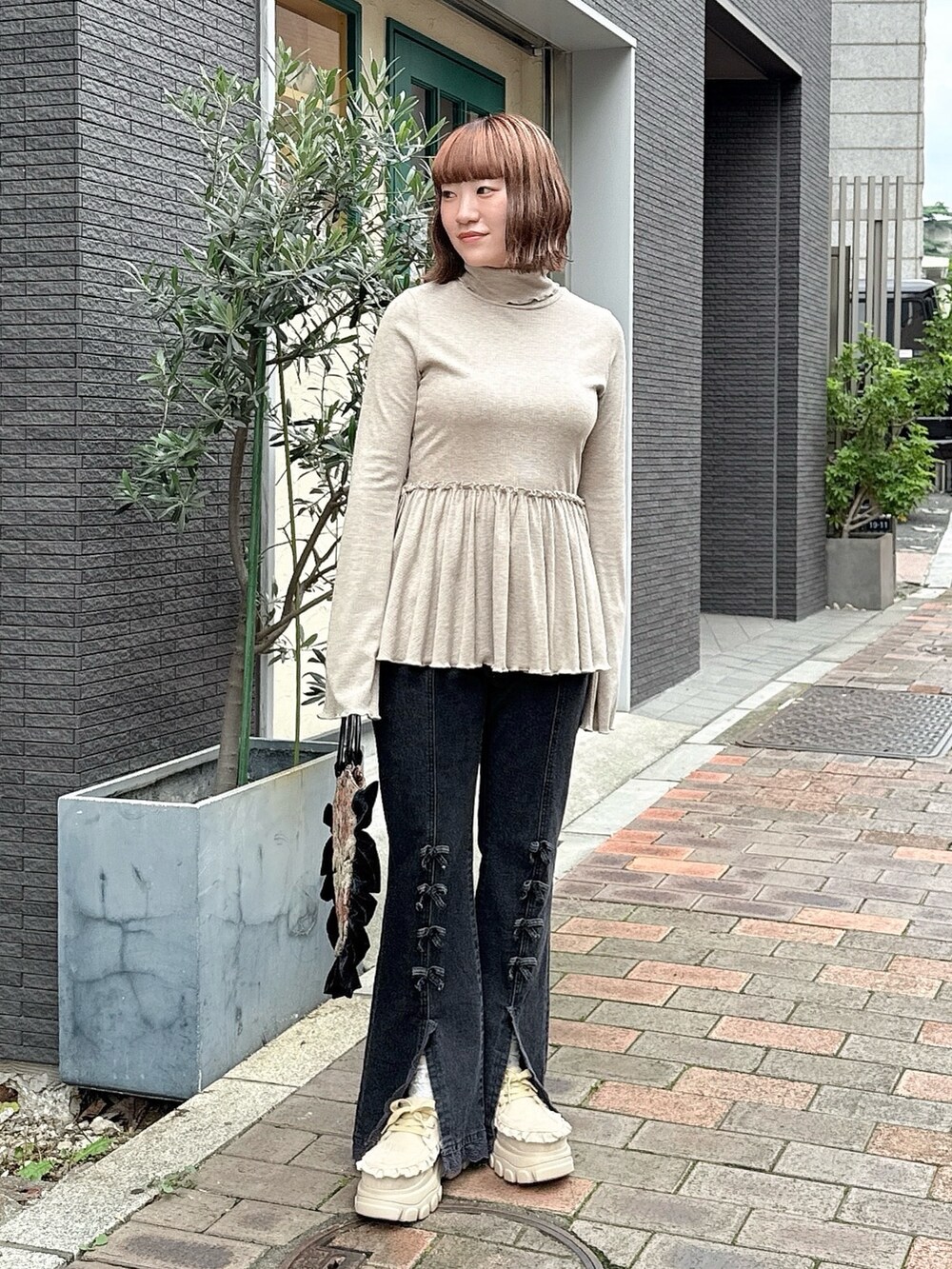 ブラウン系のニット/セーター、ブラック系のハンドバッグ、ブラック系のデニムパンツを着用したレディースの夏コーディネートの2枚目の写真