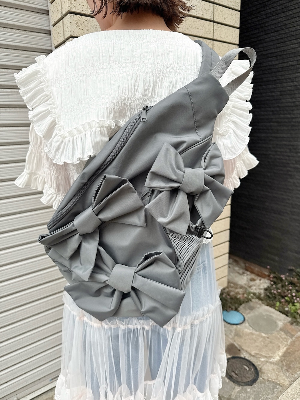 グレー系のショルダーバッグ、ホワイト系のシャツ/ブラウス、ピンク系のスカートを着用したレディースの春コーディネートの7枚目の写真