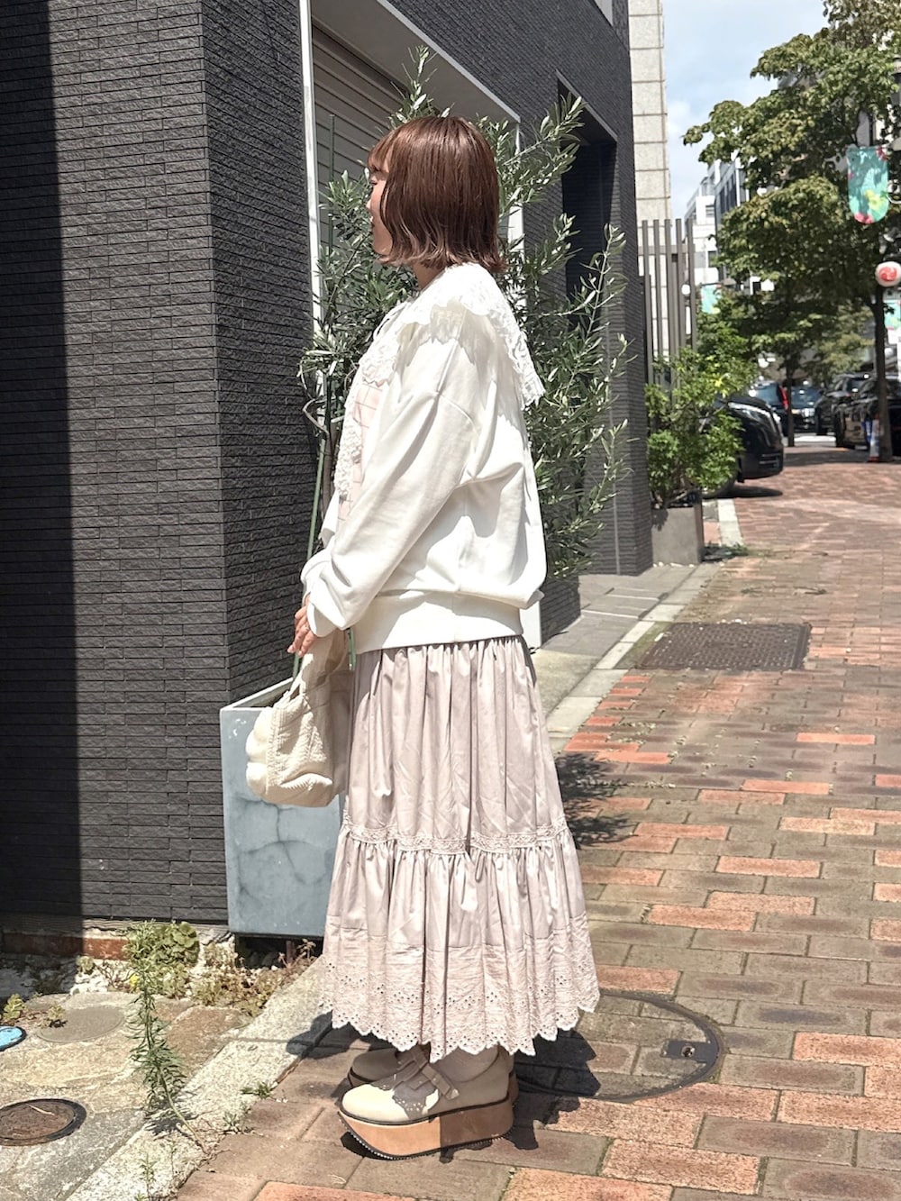 ホワイト系のバレエシューズ、ホワイト系のハンドバッグ、ホワイト系のスウェットを着用したレディースの秋コーディネートの3枚目の写真