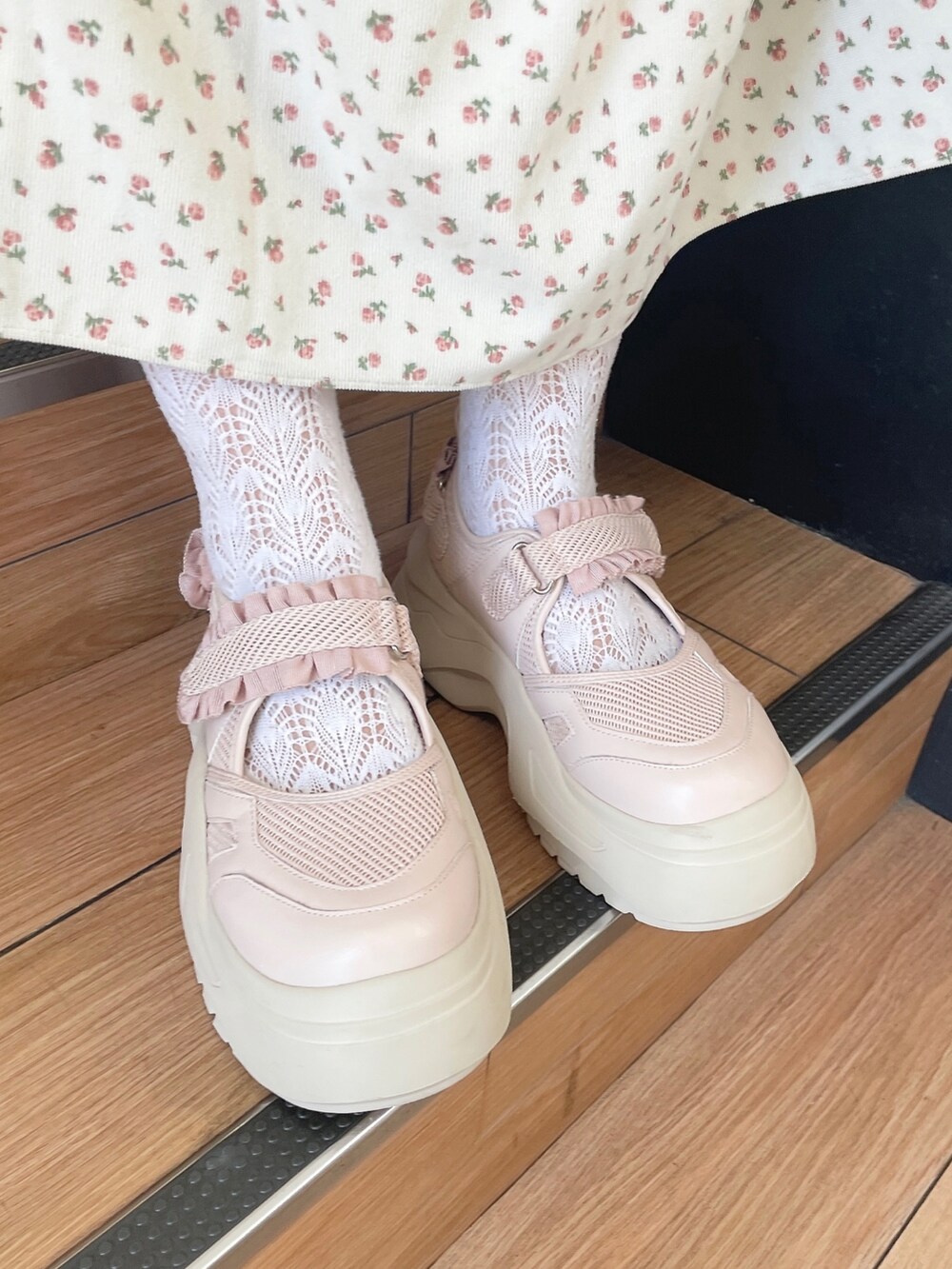ピンク系のスニーカー、ホワイト系のジャンパースカート、ホワイト系のハンドバッグを着用したレディースの秋コーディネートの5枚目の写真