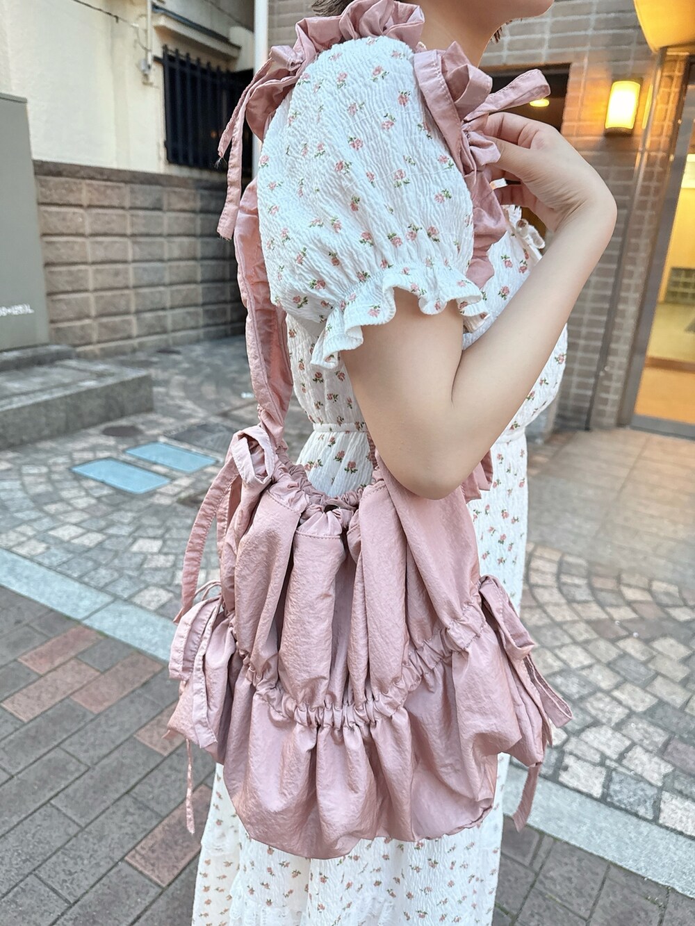 ピンク系のトートバッグ、ベージュ系のサンダル、ホワイト系のワンピースを着用したレディースの春コーディネートの7枚目の写真