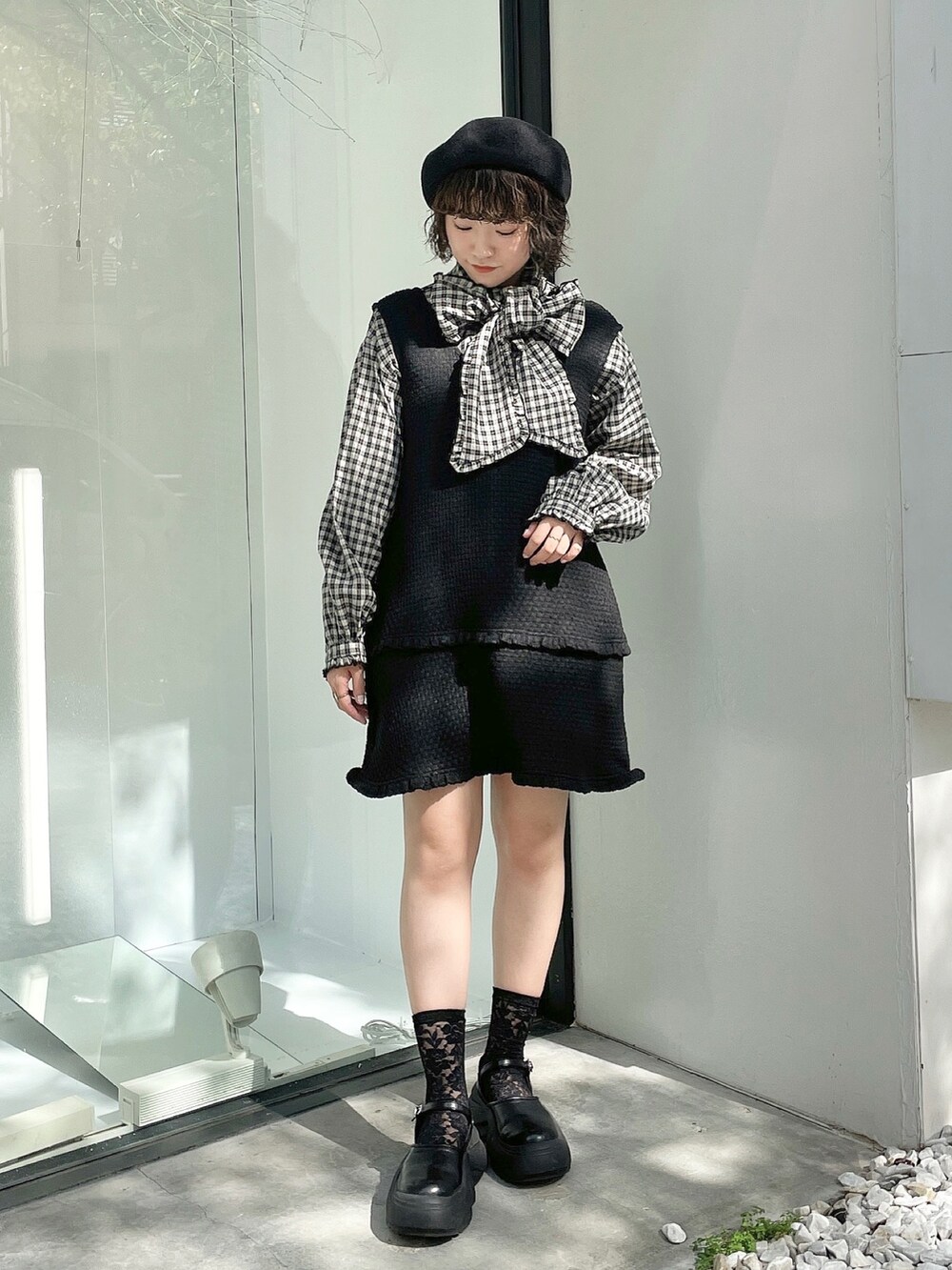 ブラック系のスニーカー、レッド系のチェスターコート、ブラック系のジャンパースカートを着用したレディースの秋コーディネートの6枚目の写真