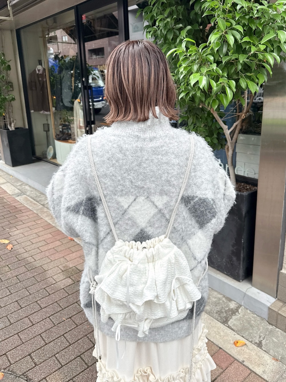 ホワイト系のスカート、グレー系のニット/セーター、ホワイト系のバックパック/リュックを着用したレディースの秋コーディネートの6枚目の写真