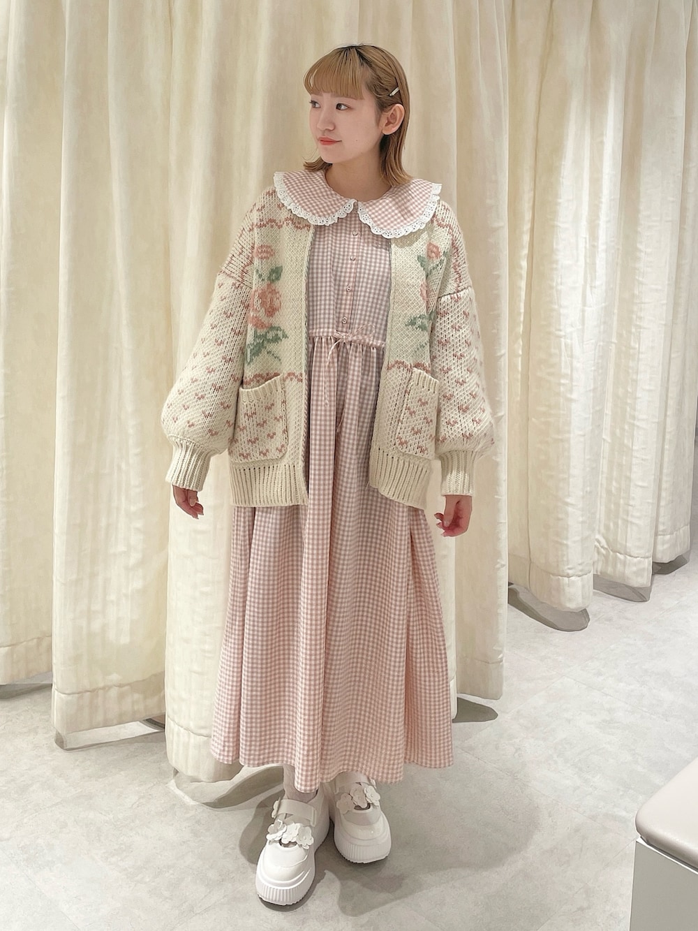 ピンク系のカーディガン/ボレロ、ピンク系のワンピース、ホワイト系のスニーカーを着用したレディースの冬コーディネートの2枚目の写真