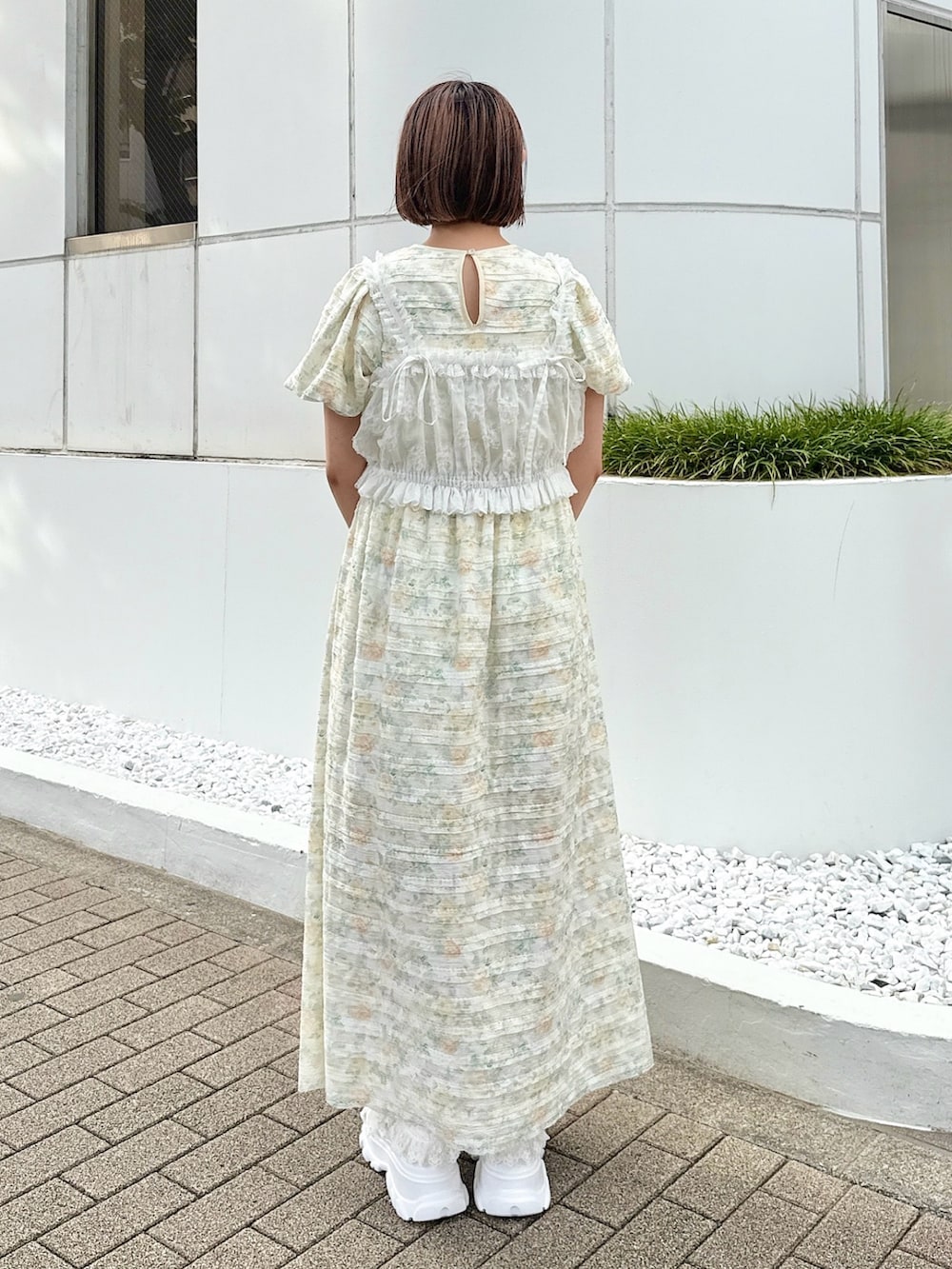 イエロー系のワンピース、ホワイト系のシャツ/ブラウス、ホワイト系のスニーカーを着用したレディースの夏コーディネートの3枚目の写真