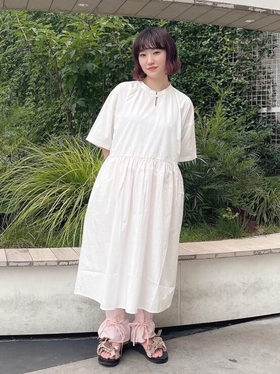 ホワイト系のワンピース、ベージュ系のサンダル、ピンク系のスラックスを着用したレディースの夏コーディネートの2枚目の写真