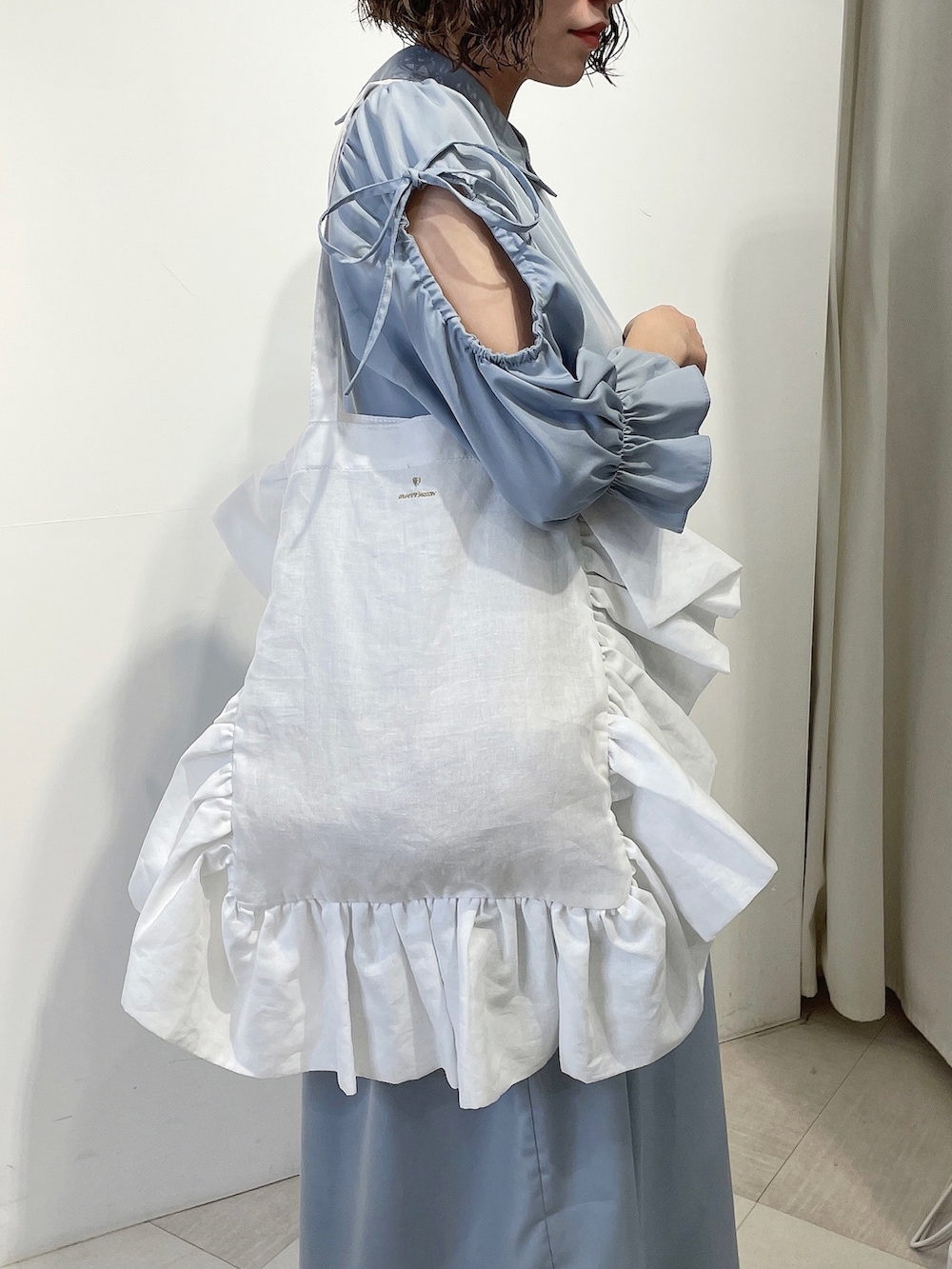 ホワイト系のトートバッグ、ブルー系のワンピース、ゴールド系のパンプスを着用したレディースの春コーディネートの6枚目の写真