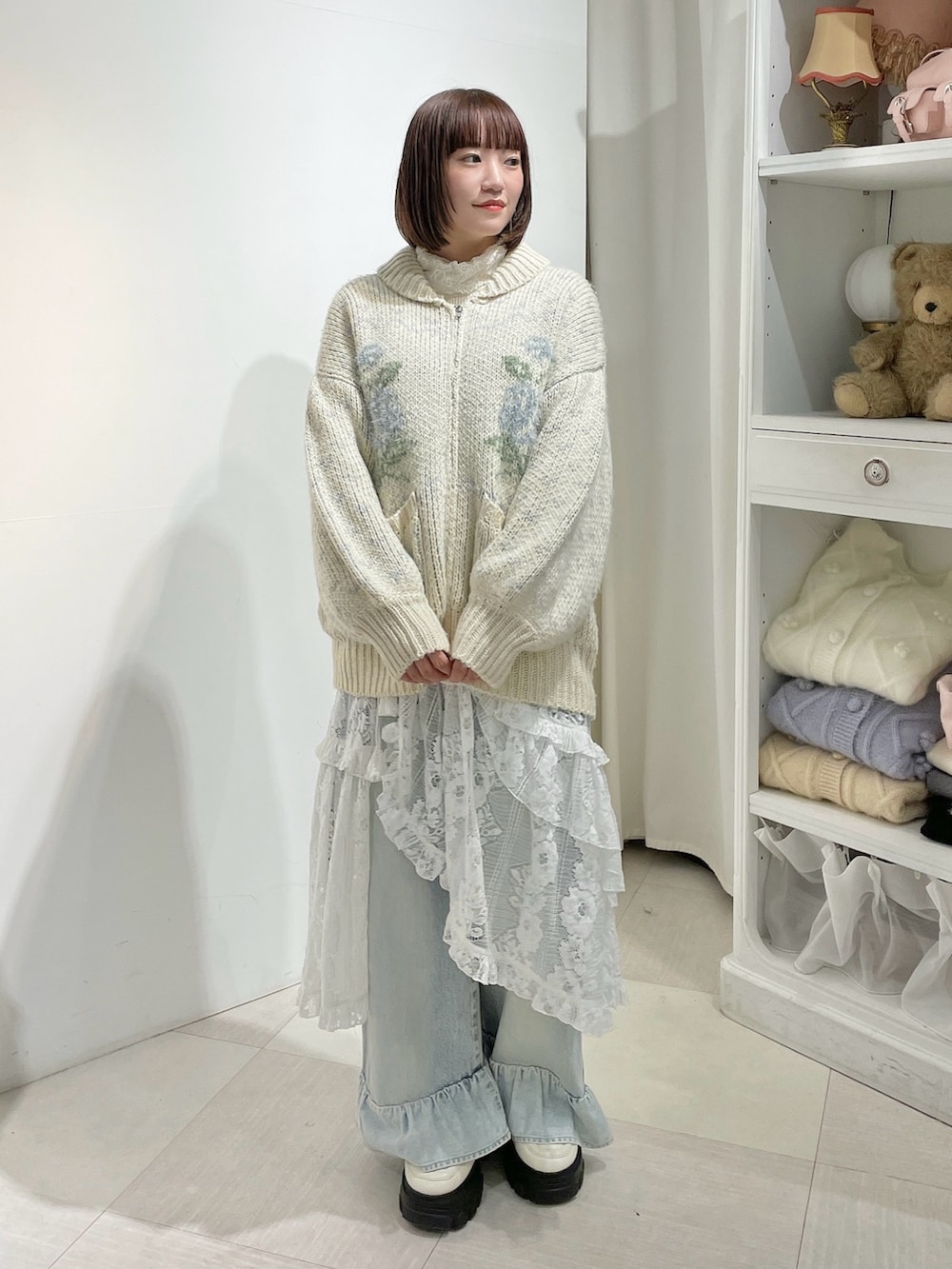 ホワイト系のニット/セーター、ブルー系のデニムパンツ、ホワイト系のスカートを着用したレディースの秋コーディネートの2枚目の写真