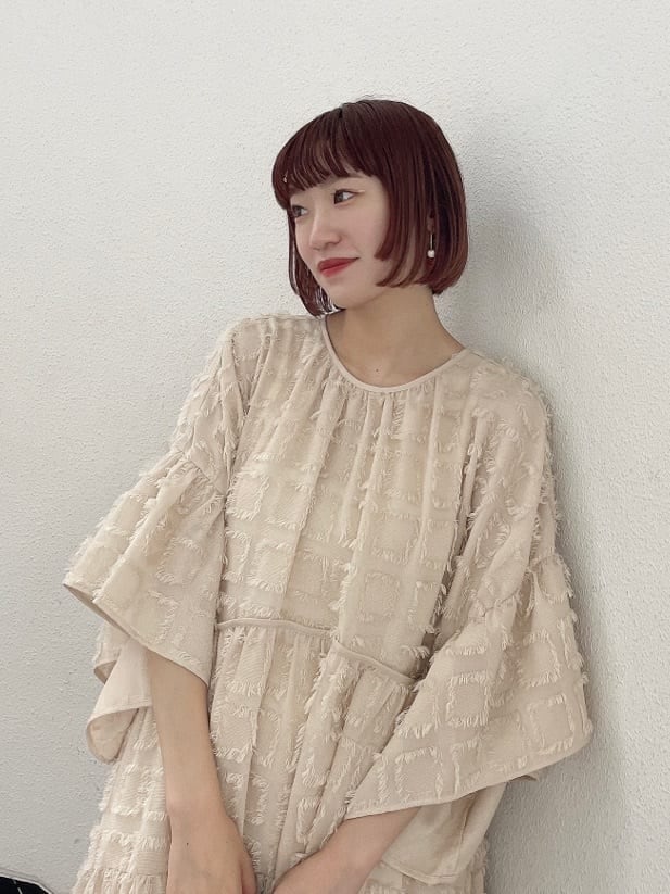 ベージュ系のドレス、グリーン系のハンドバッグ、ベージュ系のブーツを着用したレディースの夏コーディネートの5枚目の写真