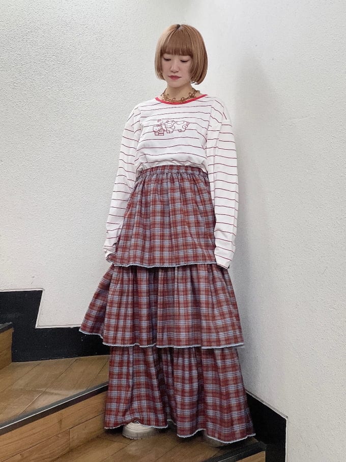レッド系のTシャツ/カットソー、オレンジ系のスカート、ホワイト系のローファーを着用したレディースの秋コーディネートの2枚目の写真