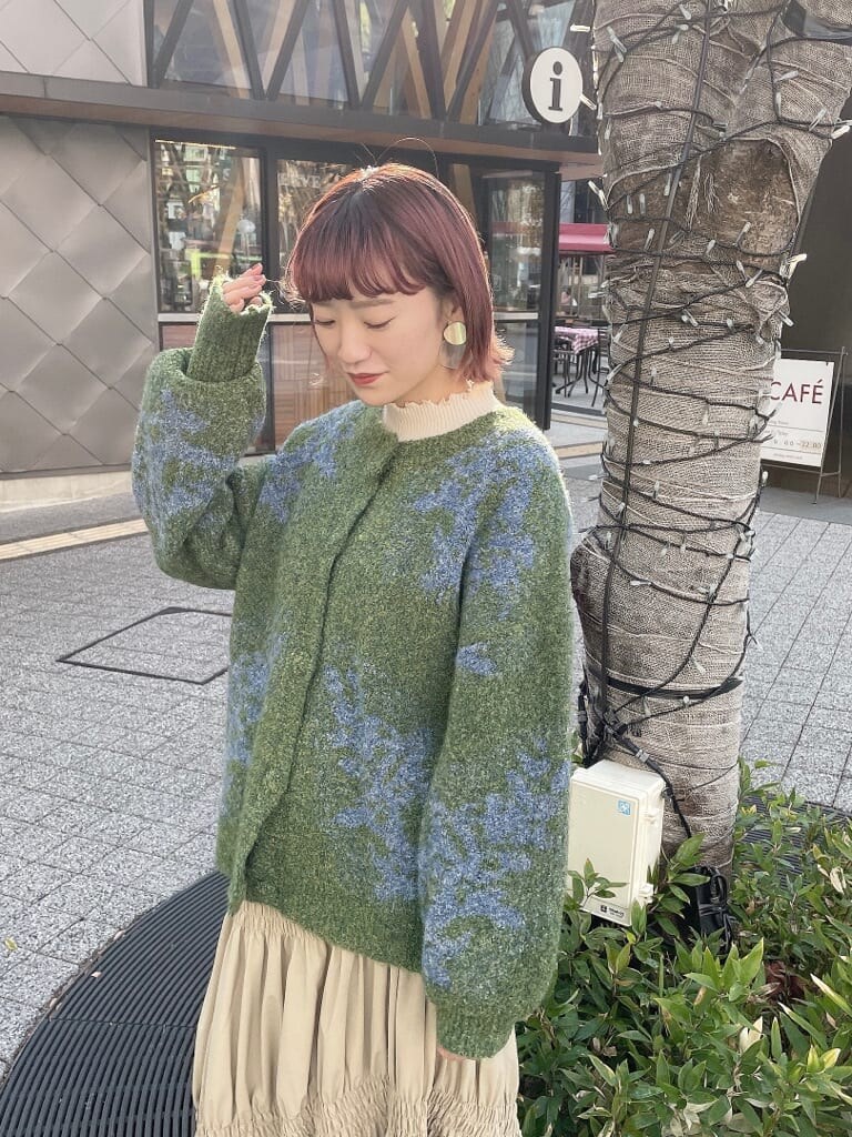 グリーン系のカーディガン/ボレロ、ベージュ系のスカート、ホワイト系のニット/セーターを着用したレディースの冬コーディネートの4枚目の写真