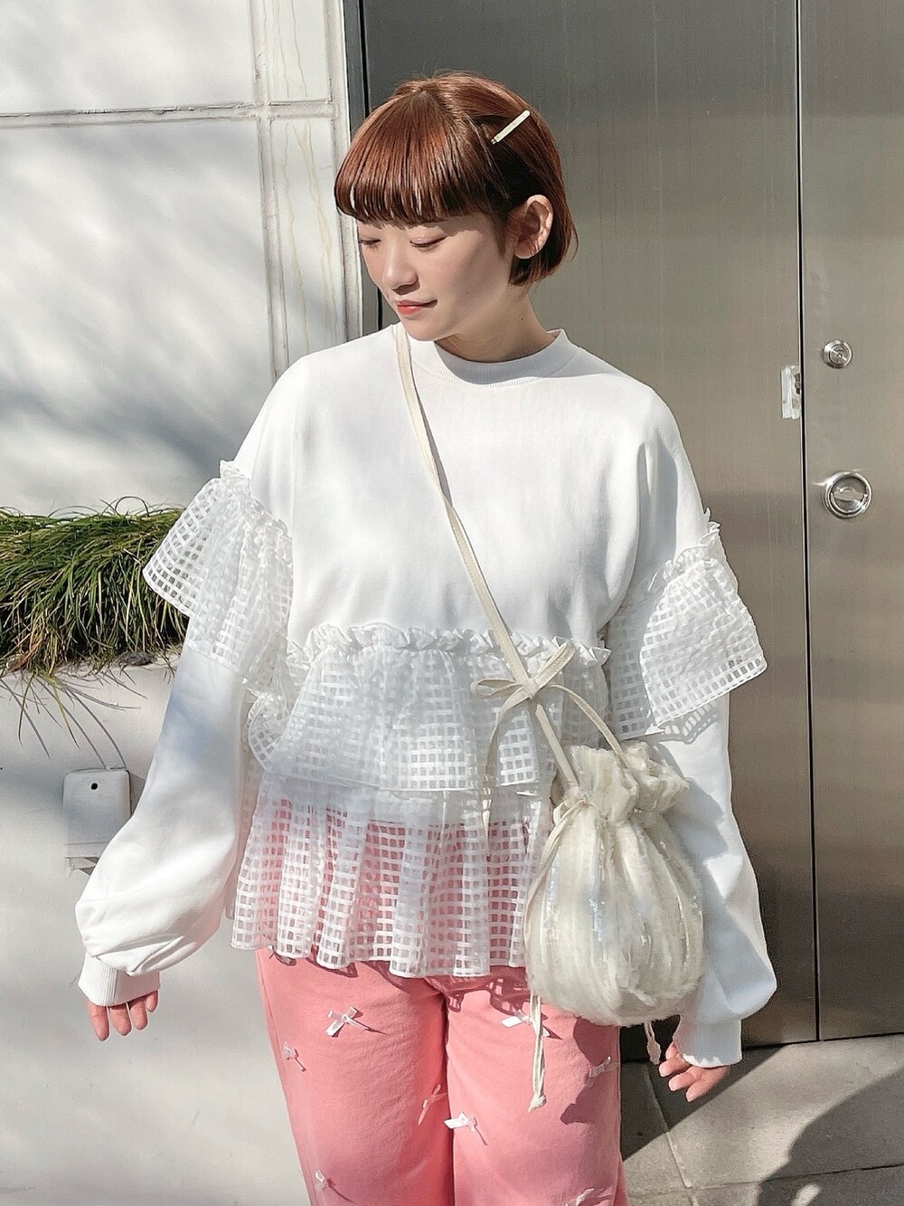 ホワイト系のスウェット、ピンク系のデニムパンツ、ホワイト系のショルダーバッグを着用したレディースの冬コーディネートの5枚目の写真