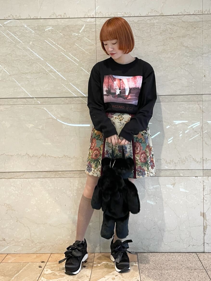 ブラック系のTシャツ/カットソー、レッド系のスカート、ブラック系のスニーカーを着用したレディースの秋コーディネートの2枚目の写真