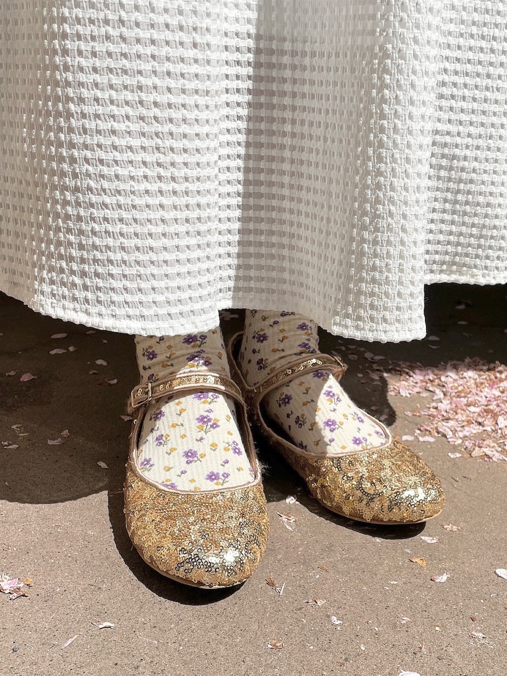 ゴールド系のパンプス、ホワイト系のチュニック、ホワイト系のワンピースを着用したレディースの春コーディネートの6枚目の写真