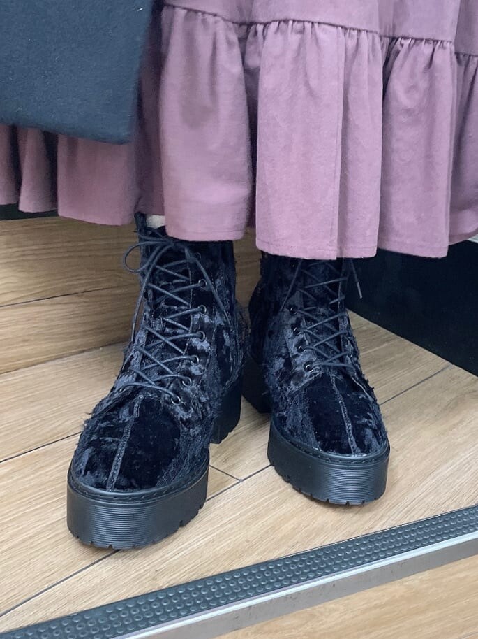 ブラック系のブーツ、ブラック系のステンカラーコート、レッド系のワンピースを着用したレディースの秋コーディネートの5枚目の写真