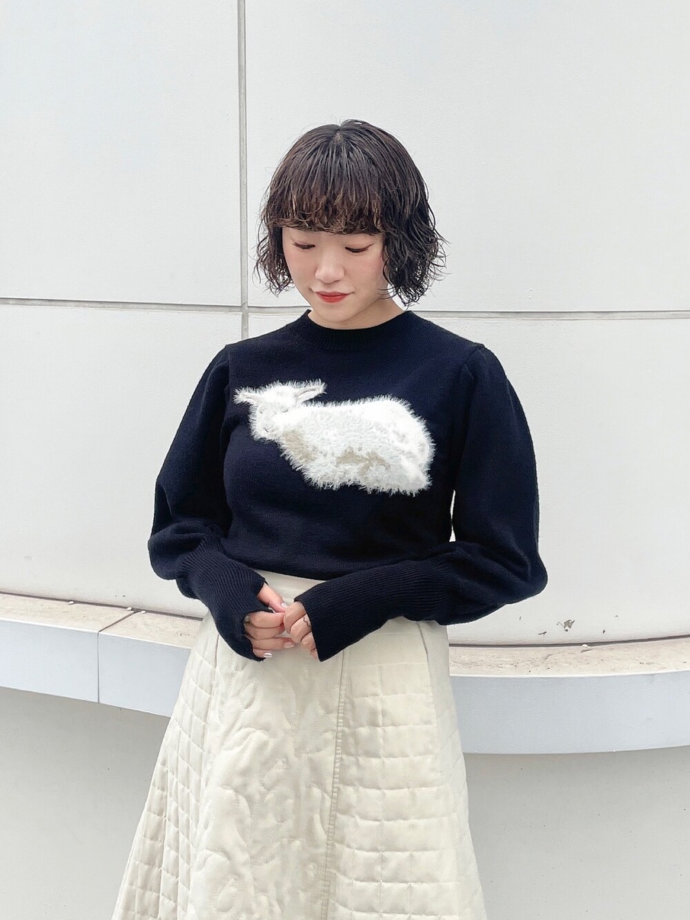 ブラック系のニット/セーター、ホワイト系のハンドバッグ、ホワイト系のスカートを着用したレディースの秋コーディネートの6枚目の写真