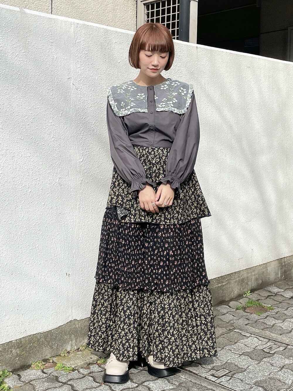 ピンク系のチェスターコート、ブラック系のスカート、グレー系のシャツ/ブラウスを着用したレディースの冬コーディネートの6枚目の写真