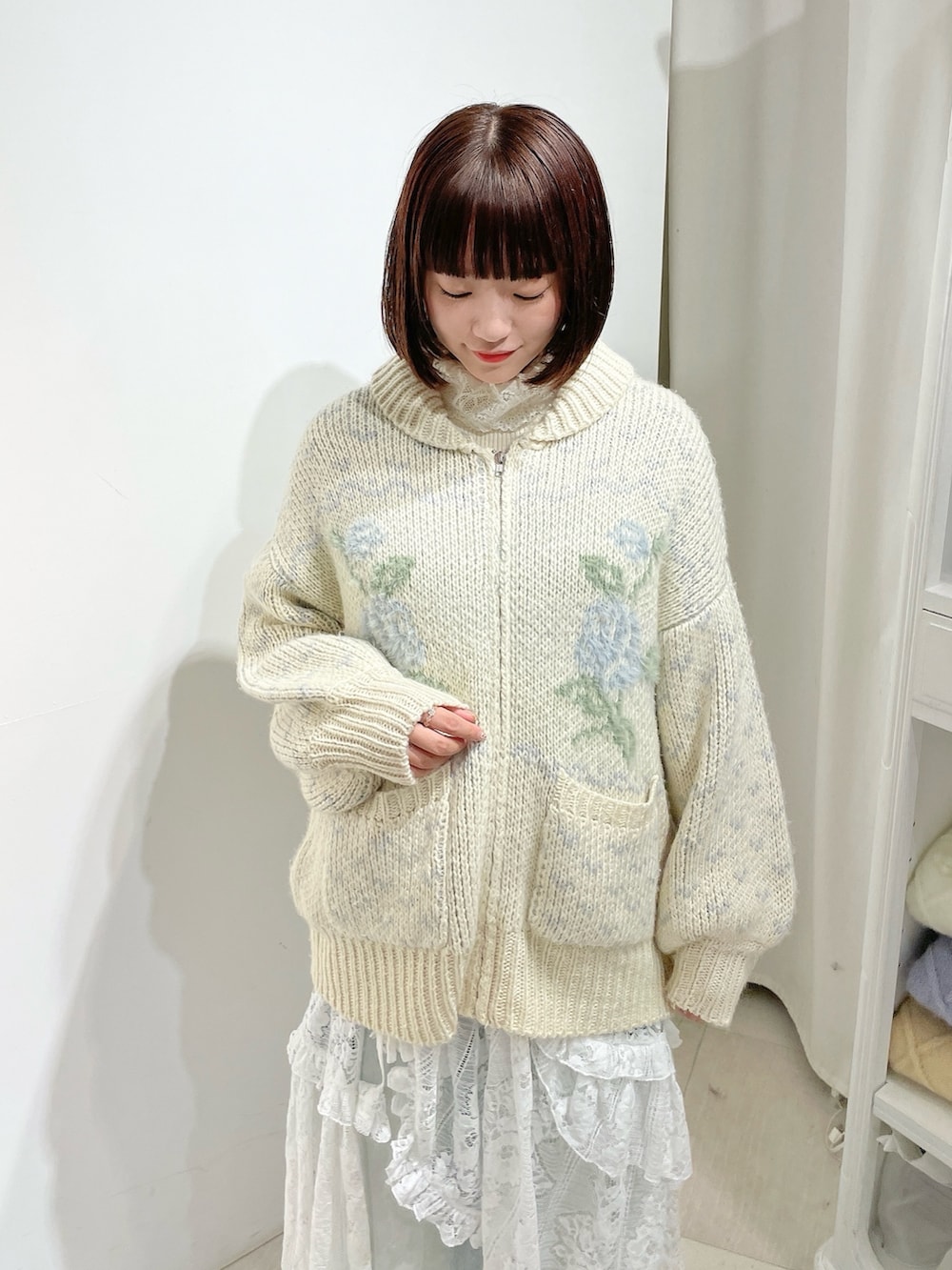 ホワイト系のニット/セーター、ブルー系のデニムパンツ、ホワイト系のスカートを着用したレディースの秋コーディネートの4枚目の写真