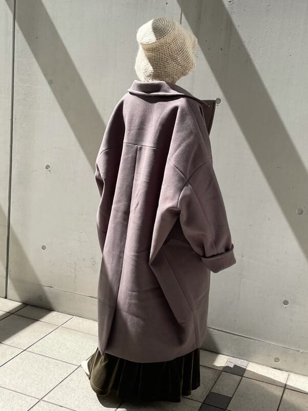 グリーン系のチェスターコート、ホワイト系のその他シューズ、ベージュ系のスカートを着用したレディースの秋コーディネートの4枚目の写真