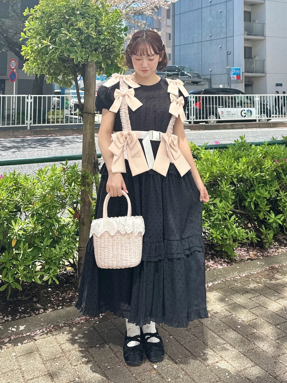 ブラック系のワンピース、ピンク系のハンドバッグ、ブラック系のバレエシューズを着用したレディースの春コーディネートの2枚目の写真