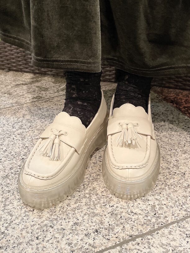 ベージュ系のスカート、ホワイト系のローファー、グリーン系のショルダーバッグを着用したレディースの冬コーディネートの8枚目の写真