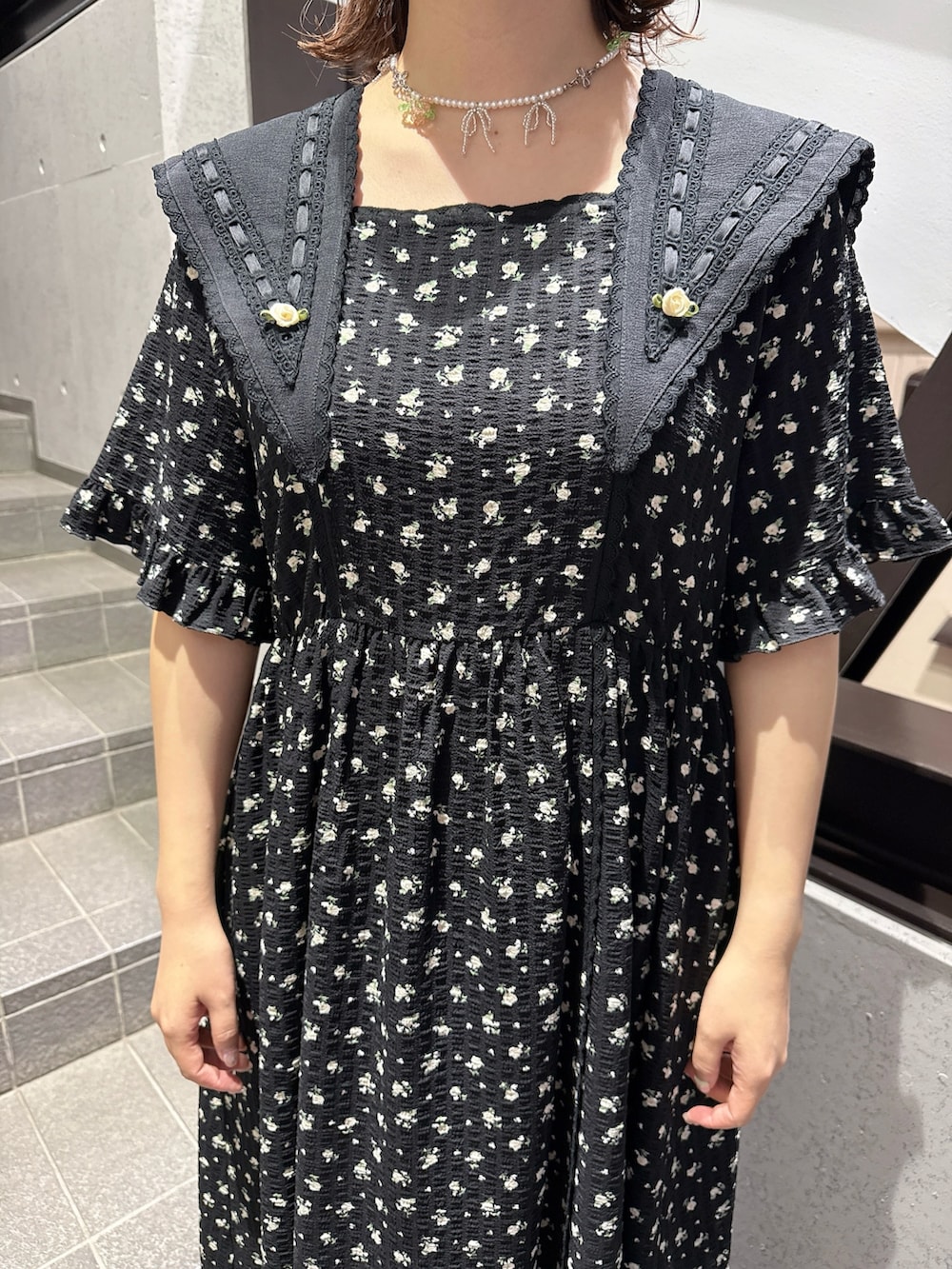 ブラック系のワンピース、ブラック系のスニーカー、ピンク系のネックレスを着用したレディースの春コーディネートの6枚目の写真