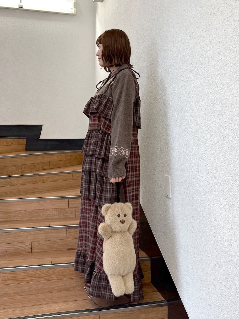 ブラウン系のニット/セーター、レッド系のワンピース、ベージュ系のハンドバッグを着用したレディースの秋コーディネートの3枚目の写真