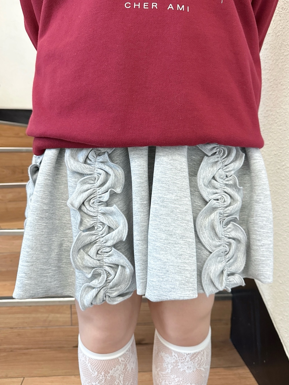 レッド系のスウェット、グレー系のスカート、ブラウン系のハンドバッグを着用したレディースの夏コーディネートの6枚目の写真