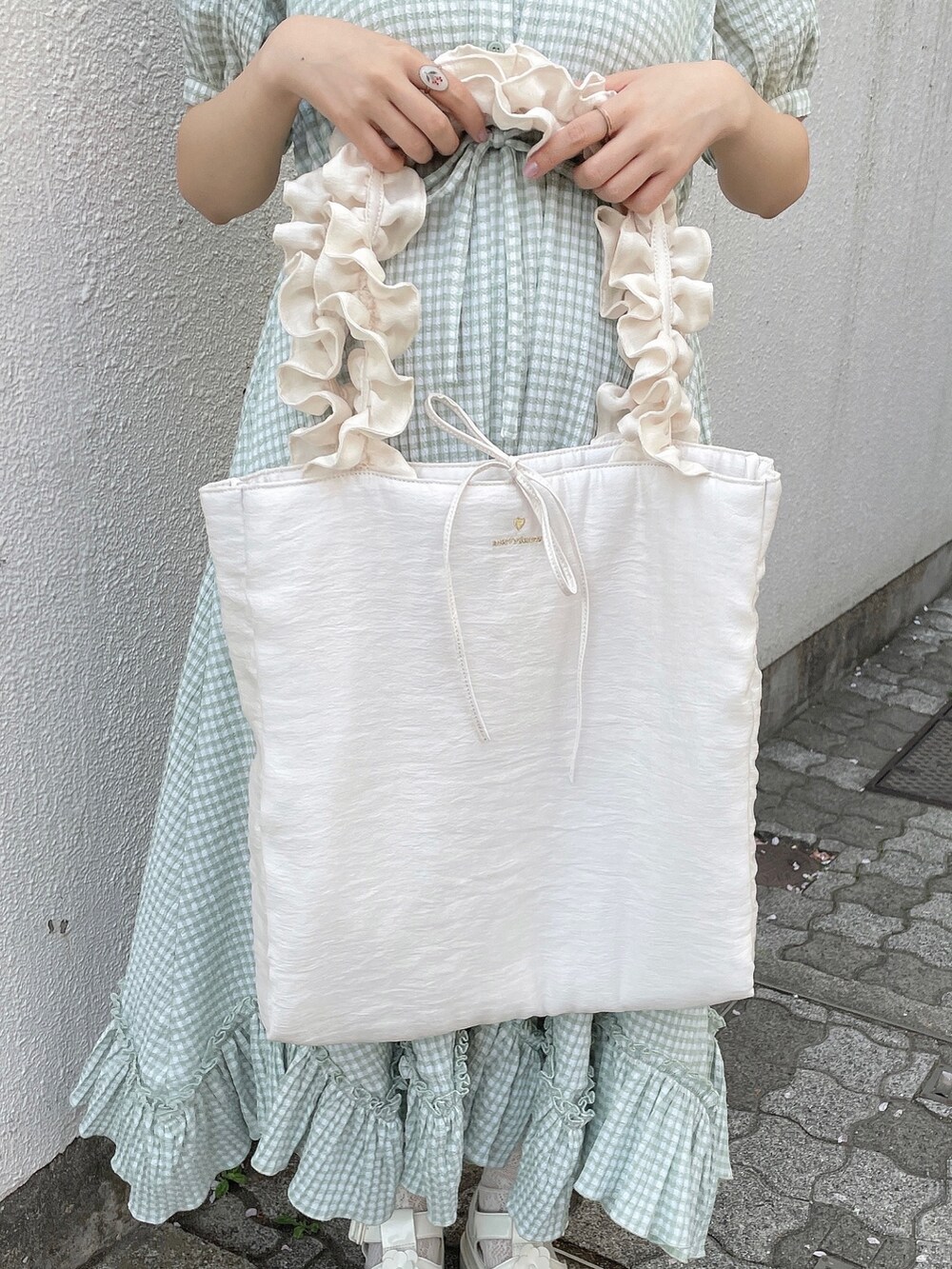 グリーン系のワンピース、ホワイト系のトートバッグ、ホワイト系のサンダルを着用したレディースの春コーディネートの9枚目の写真