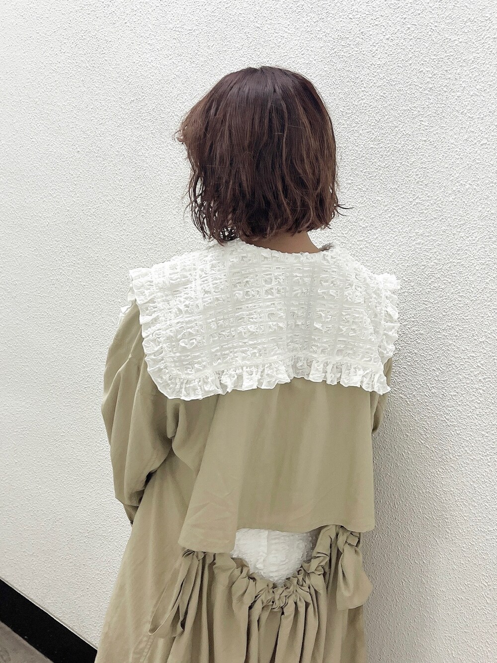 ホワイト系のワンピース、ベージュ系のトレンチコート、ホワイト系のパンプスを着用したレディースの冬コーディネートの5枚目の写真