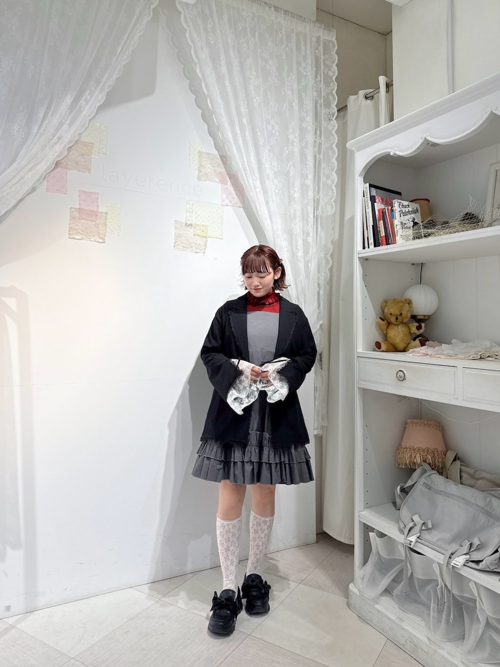 レッド系のニット/セーター、グレー系のワンピース、ブラック系のテーラードジャケットを着用したレディースの冬コーディネートの2枚目の写真