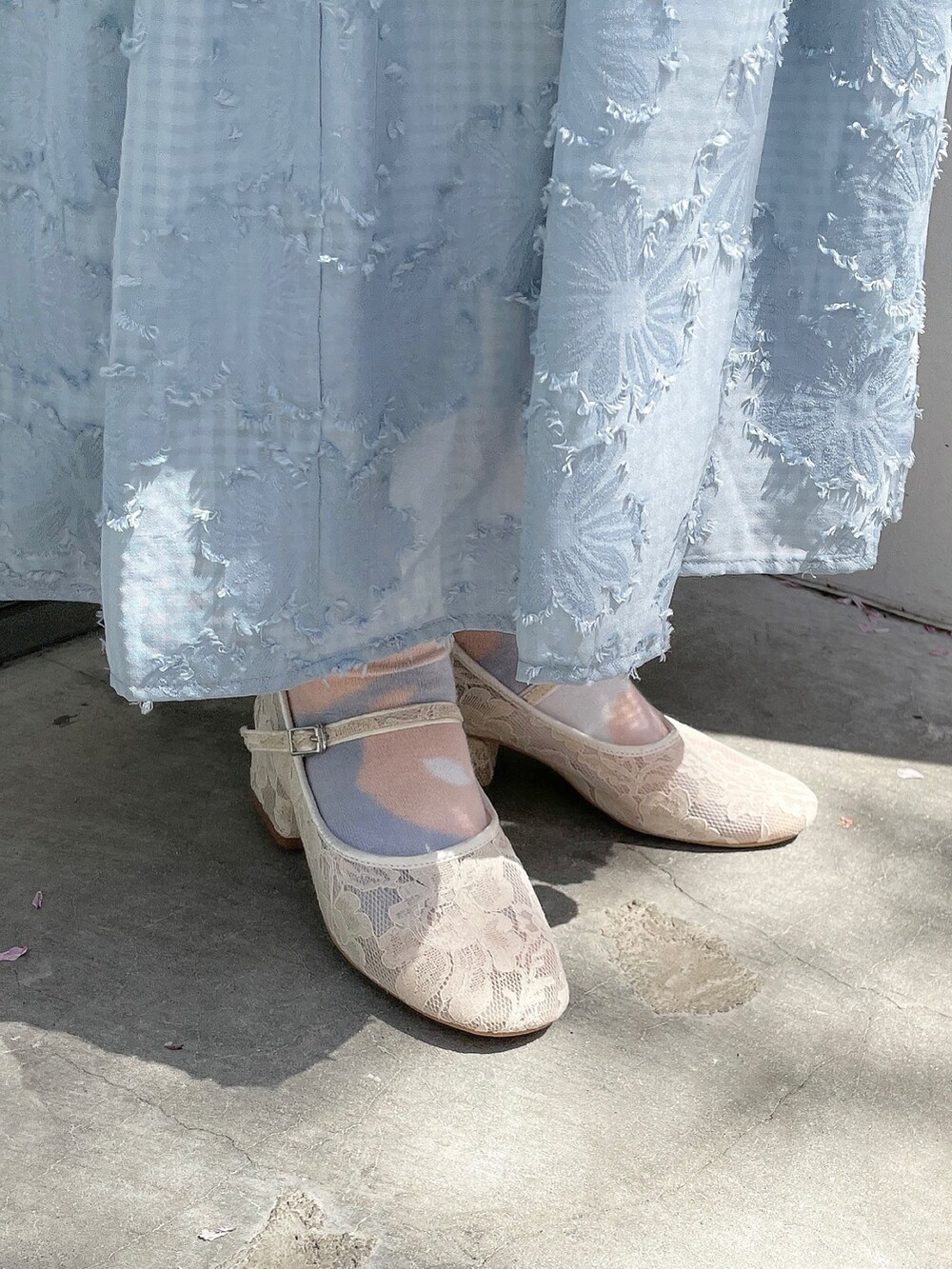 ブルー系のスカート、ホワイト系のニット/セーター、ホワイト系のパンプスを着用したレディースの春コーディネートの5枚目の写真